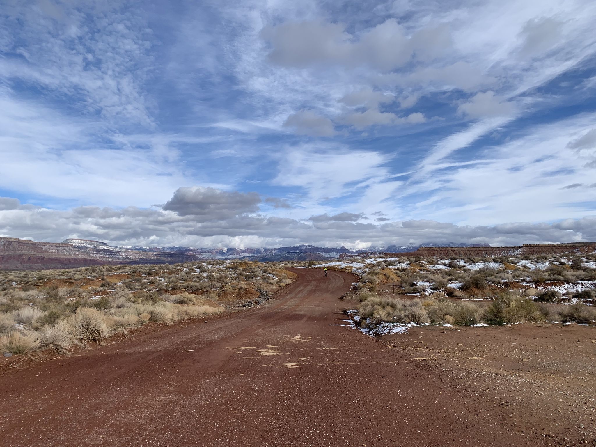 A wide dirt road through a snowy, arid landscape under a cloudy sky. - Upper JEM Trail loop from Site 1