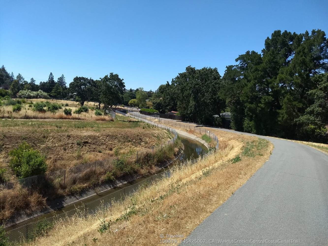 Paved path beside a fenced canal, with trees and dry grass. - Iron Horse and Contra Costa Canal Trail Loop