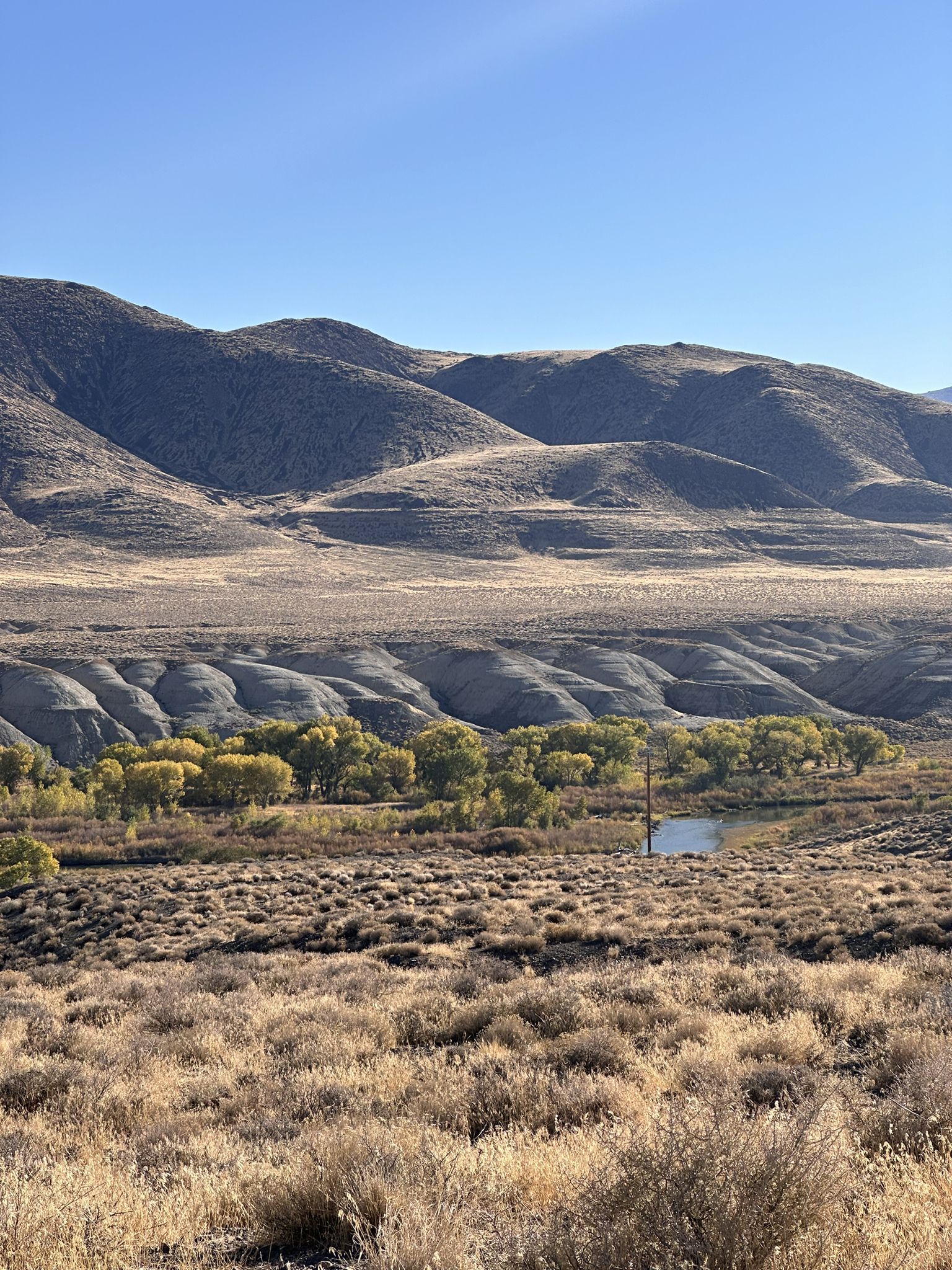 Wide valley with rolling hills, autumn trees, and a small body of water. - Wadsworth, Nevada to Pyramid Lake
