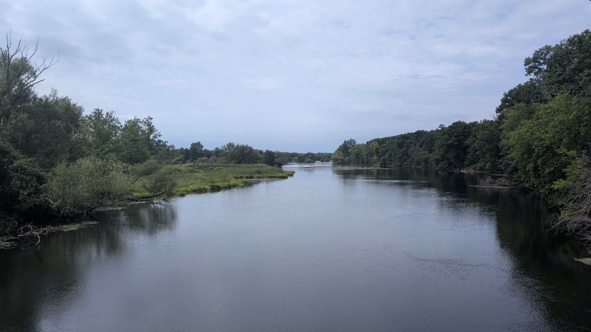 Wide river flowing through green forested banks under an overcast sky. - Kalamazoo River Valley Trail and Morrow Lake Loop