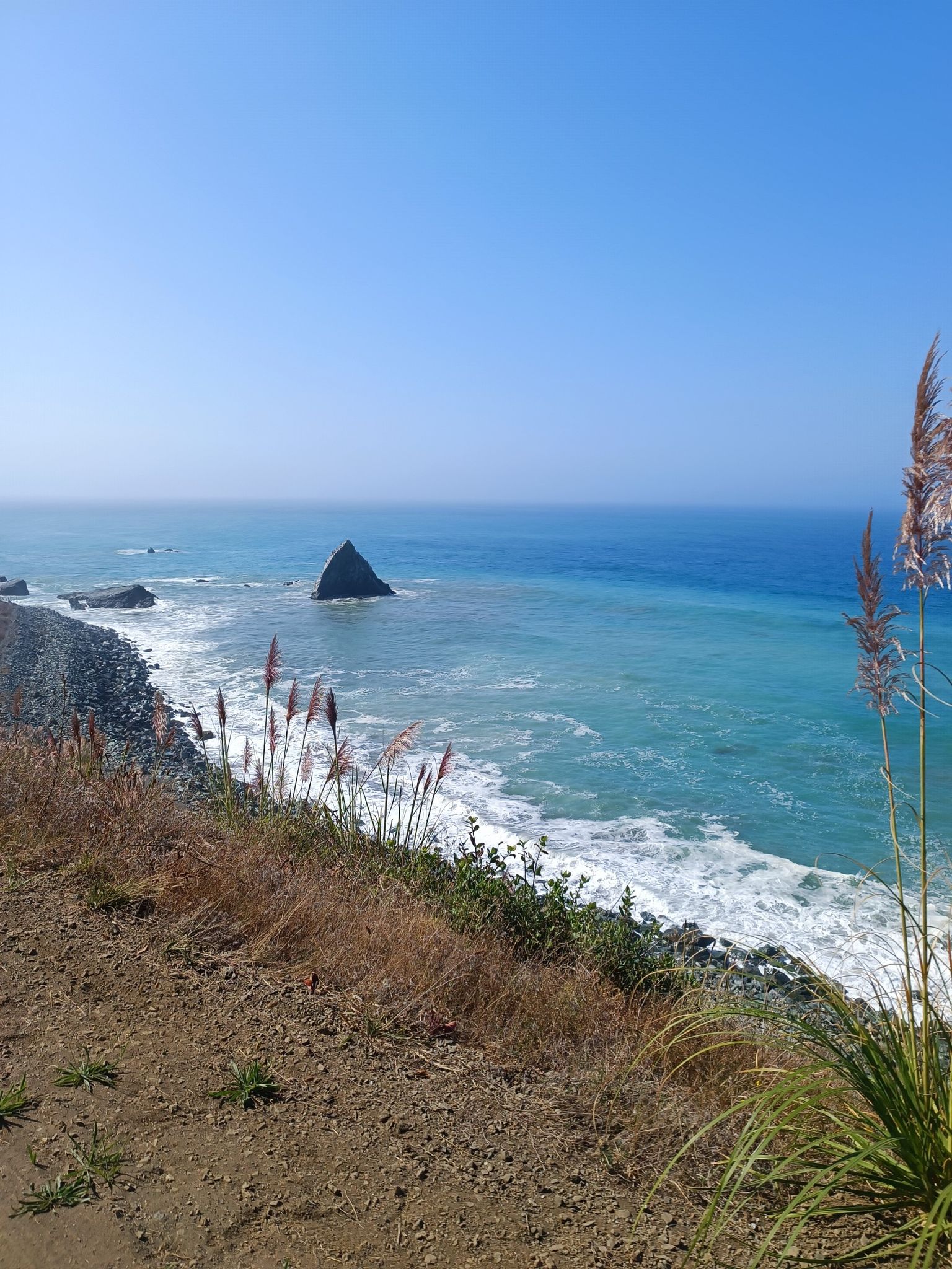 Rocky beach with ocean waves and a prominent sea stack, clear sky. - Leggett to Westport via California State Route 1