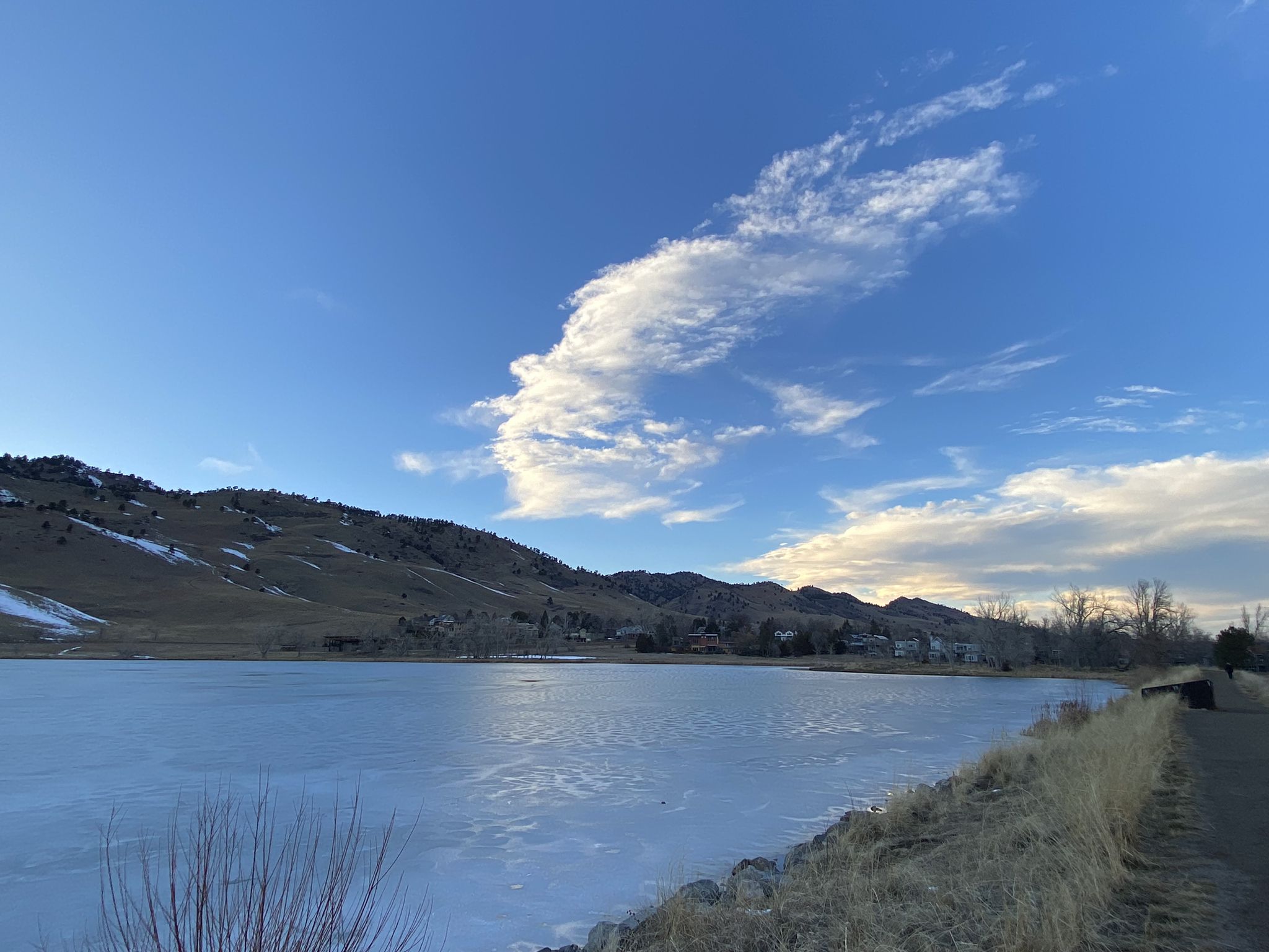 A frozen lake with snow-dusted hills and a bright blue sky with wispy clouds. - B360 Loop