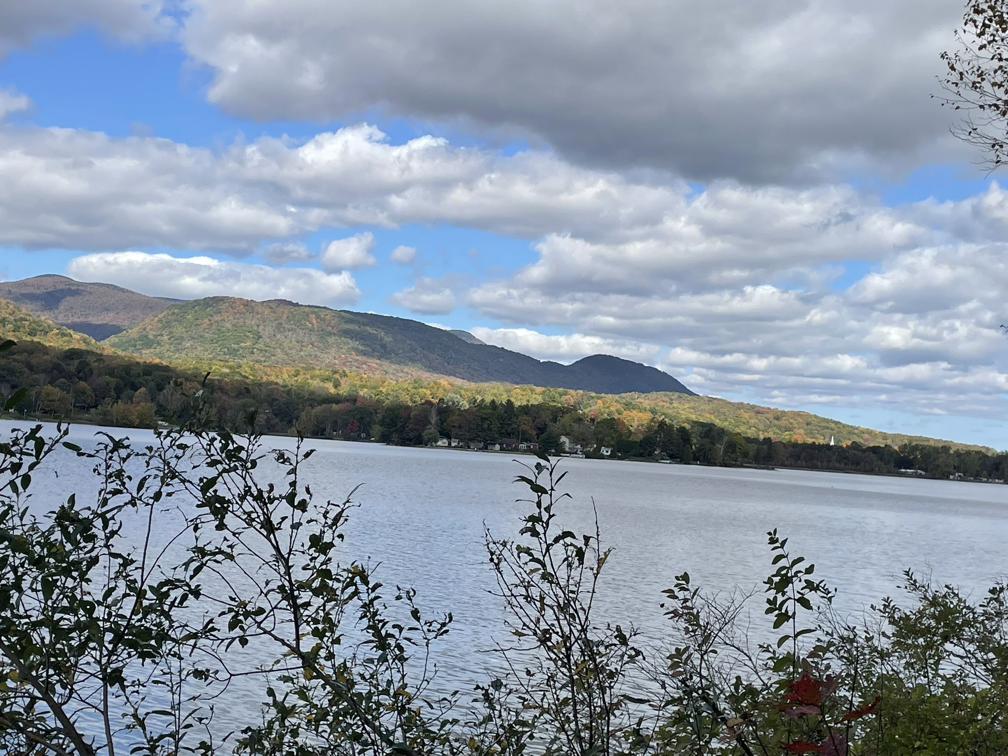 A large lake with forested mountains under a cloudy sky, autumn foliage. - Ashuwillticook Rail Trail