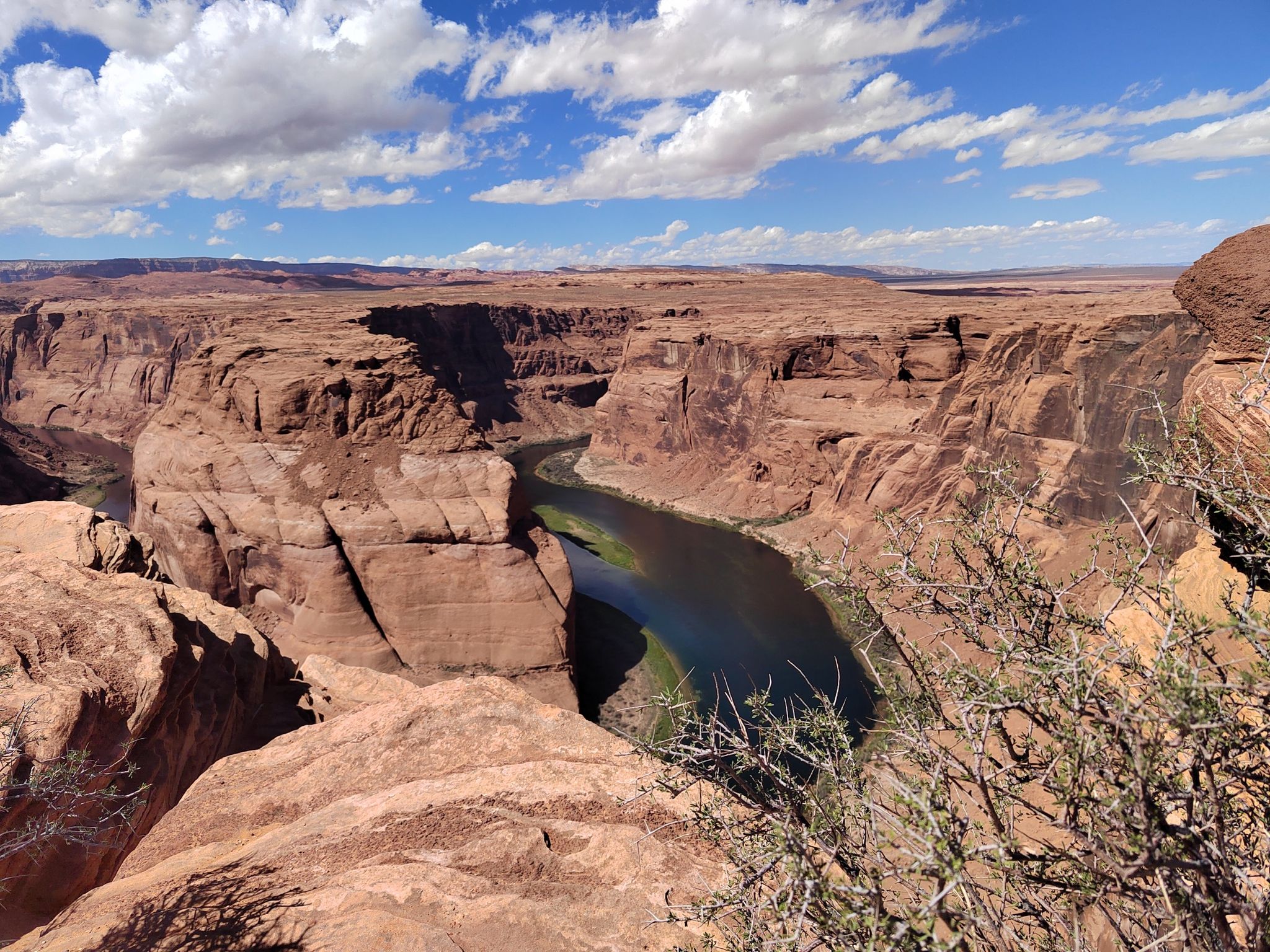 River winding through a deep red rock canyon under a partly cloudy sky. - Horseshoe Bend Trail