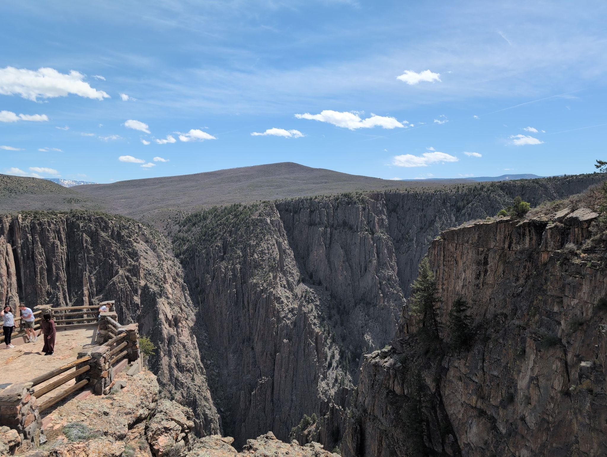 Wide canyon view with distant mountains, blue sky, and people on an overlook. - Oak Flat Loop Trail