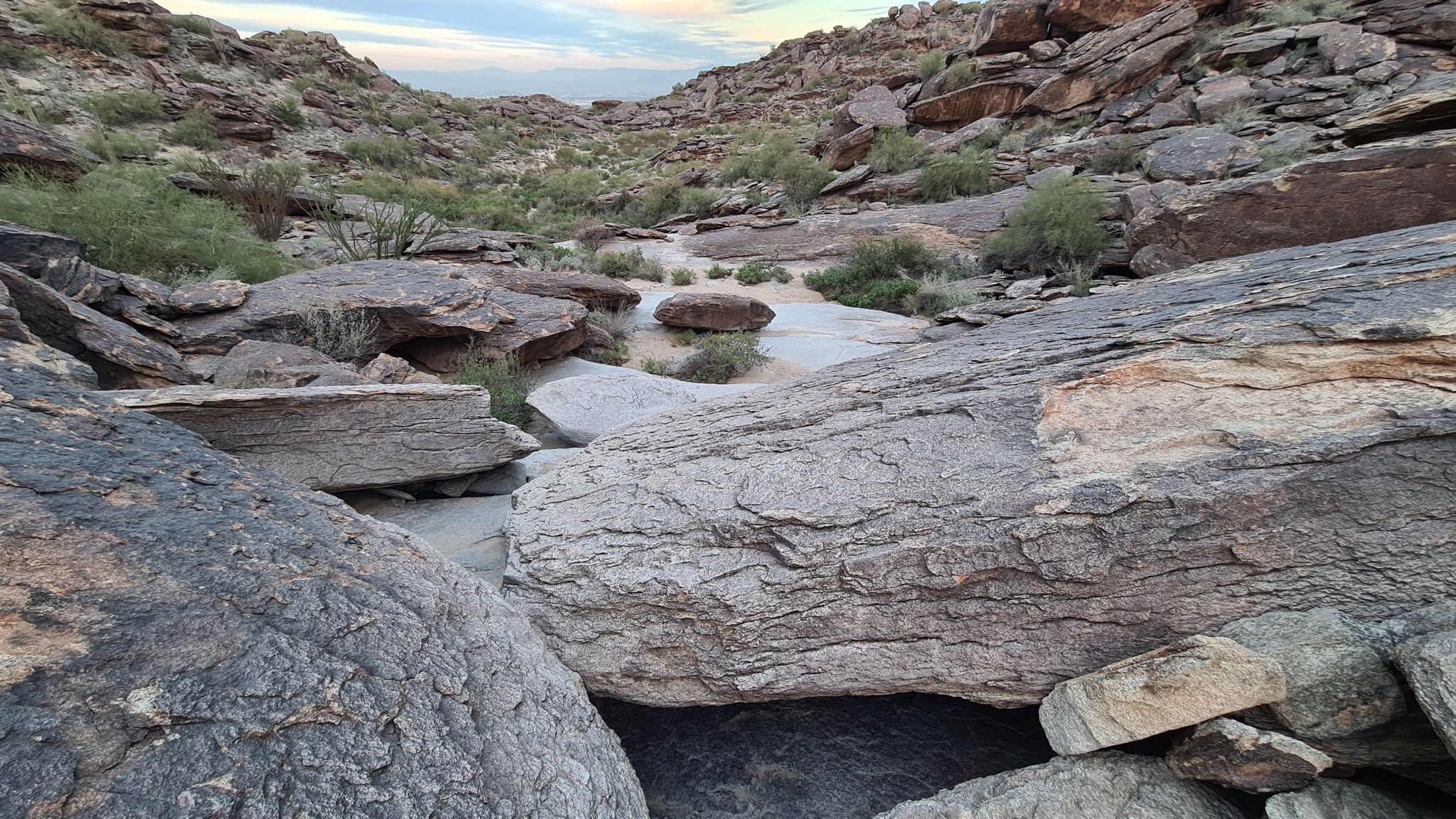 Rocky desert wash with pools of water under a cloudy sky. - National Trail to Mormon Loop