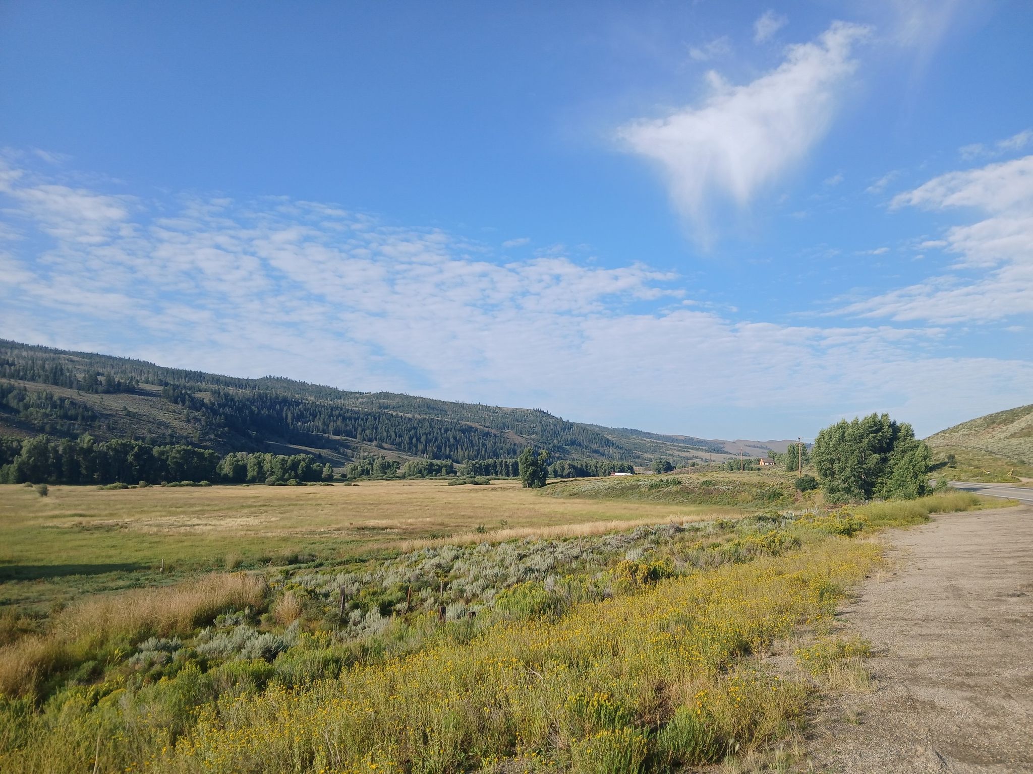 Expansive green valley with distant forested hills under a bright blue sky. - From Kremmling to Lake Granby – Way and Return