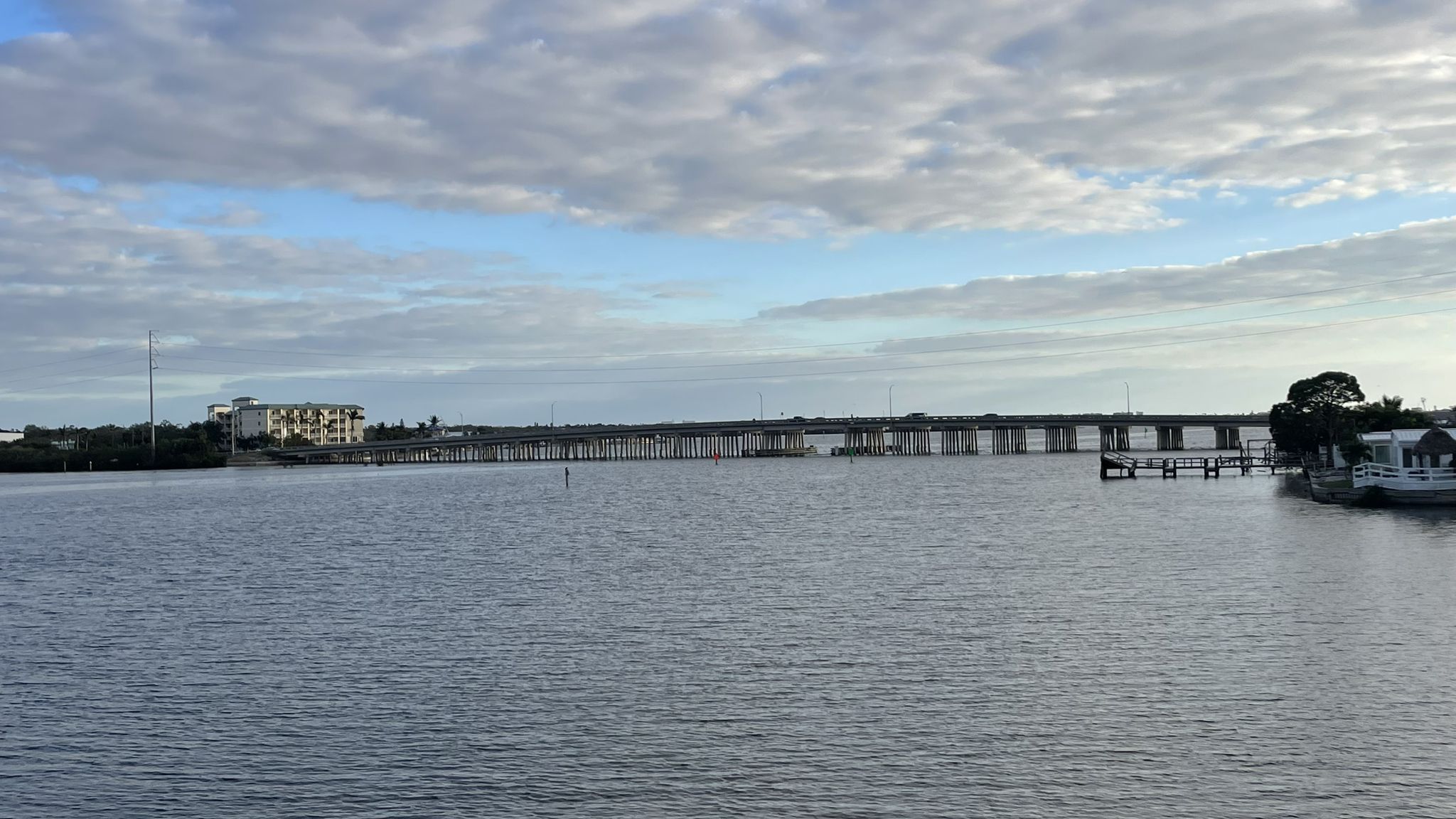 Long bridge over calm water with buildings under a cloudy sky. - Clam Bayou View – Clam Bayou Nature Preserve loop from Madeira Beach