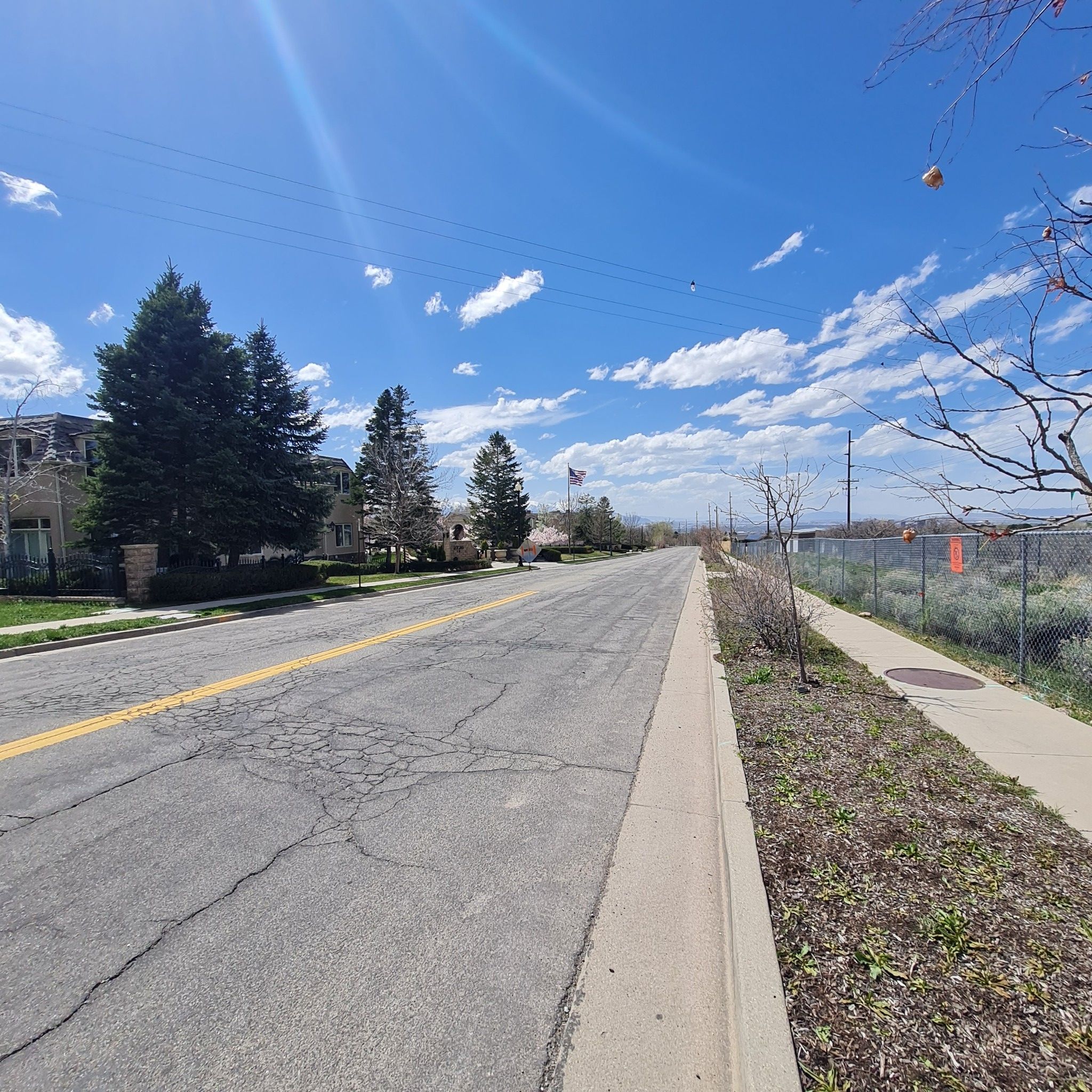 A wide road and sidewalk with trees under a bright, partly cloudy sky. - Utah's Hogle Zoo – Bells Canyon Granite Trailhead loop from Historic Sandy
