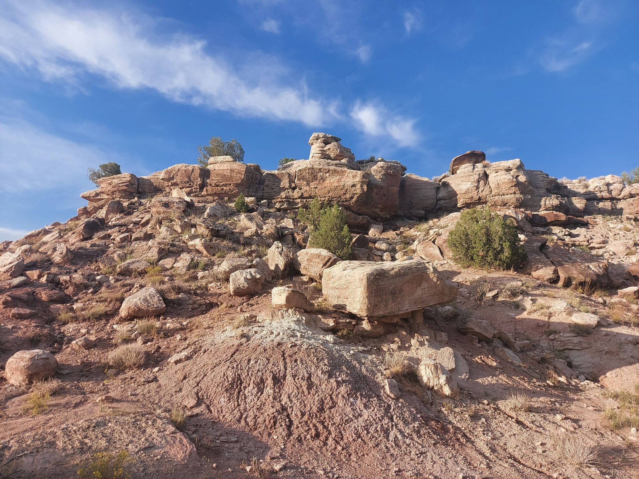 Sunny view of a rocky, reddish-brown hillside with sparse green bushes. - Kodel 1 Loop