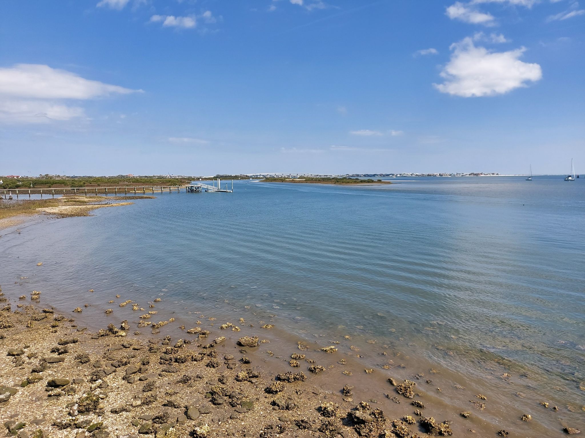 Wide view of calm bay with rocky shore under blue sky. - East Coast Greenway Trail
