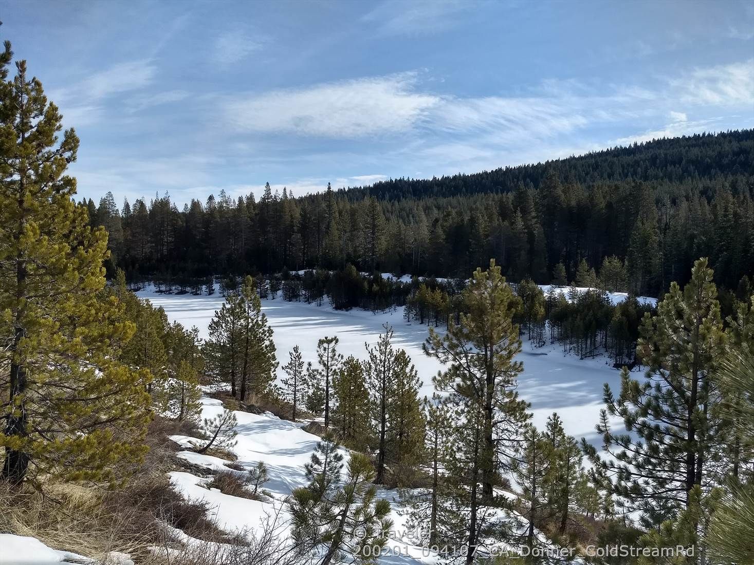 Frozen lake surrounded by snow-covered pine trees under a partly cloudy winter sky. - Cold Stream Road to South Shore Drive loop