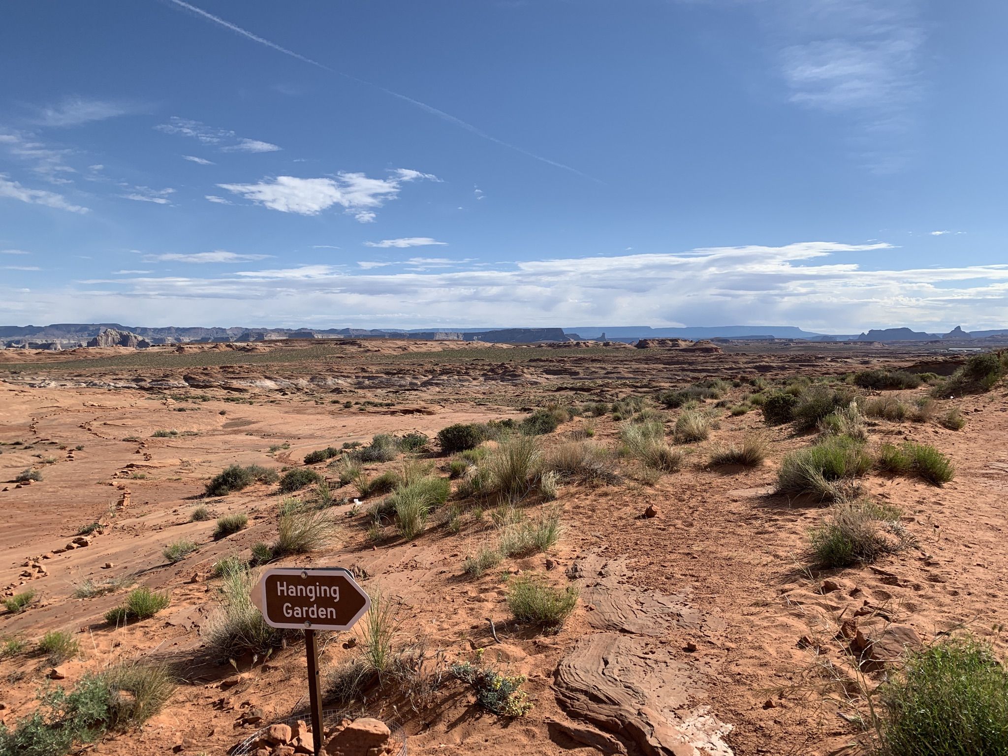 Desert landscape with sparse vegetation and a brown sign pointing right. - Glen Canyon Dam Bridge – Glen Canyon Dam loop from Glen Canyon Dam
