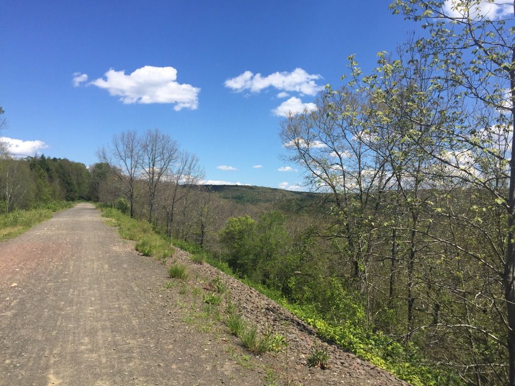 Gravel path overlooking a vast green valley under a blue sky. - Air Line State Park Trail – Former Lyman Viaduct loop from Portland Air Line Trail Spur