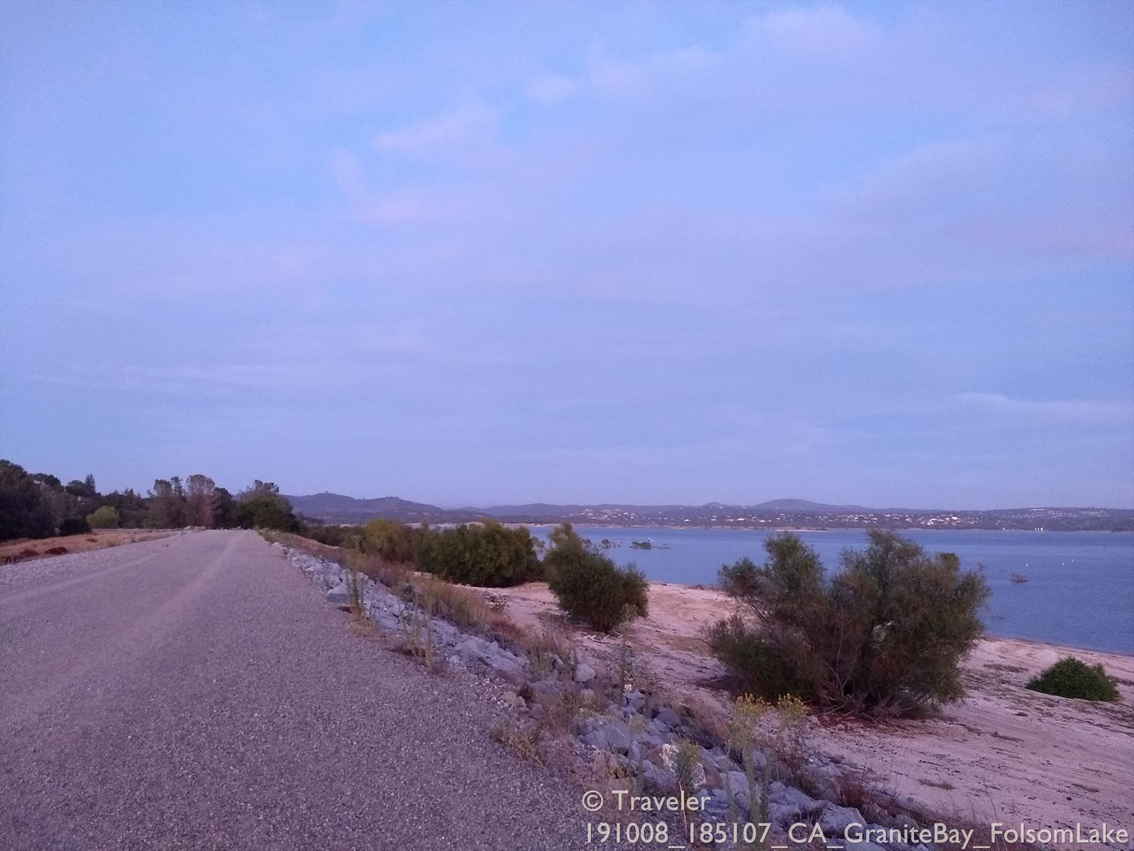 Gravel road beside a large lake at dusk with soft purple light. - Views of Folsom Lake – West Beach of Folsom Lake loop from Browns Ravine Cove