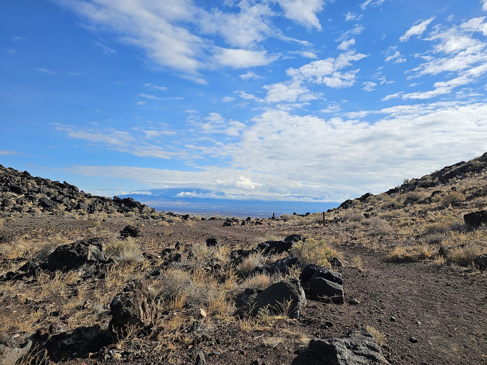 Rocky desert landscape under a bright blue sky with distant hazy mountains. - Volcano and Petroglyph Trail