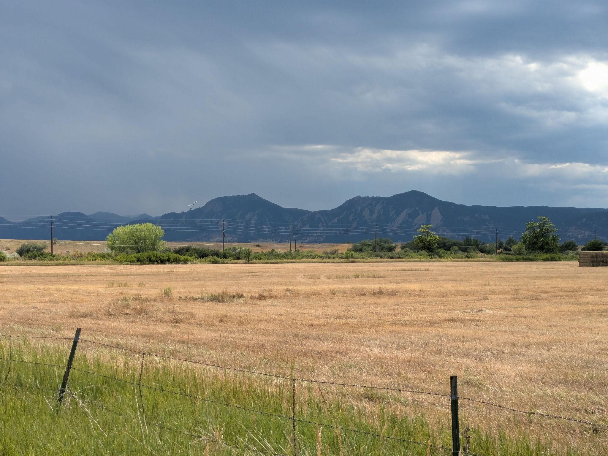 Dry field with distant mountains under a dramatic, cloudy sky. - Boulder Reservoir loop via 63rd Street, Niwot Road, and 36 from Pearl Street