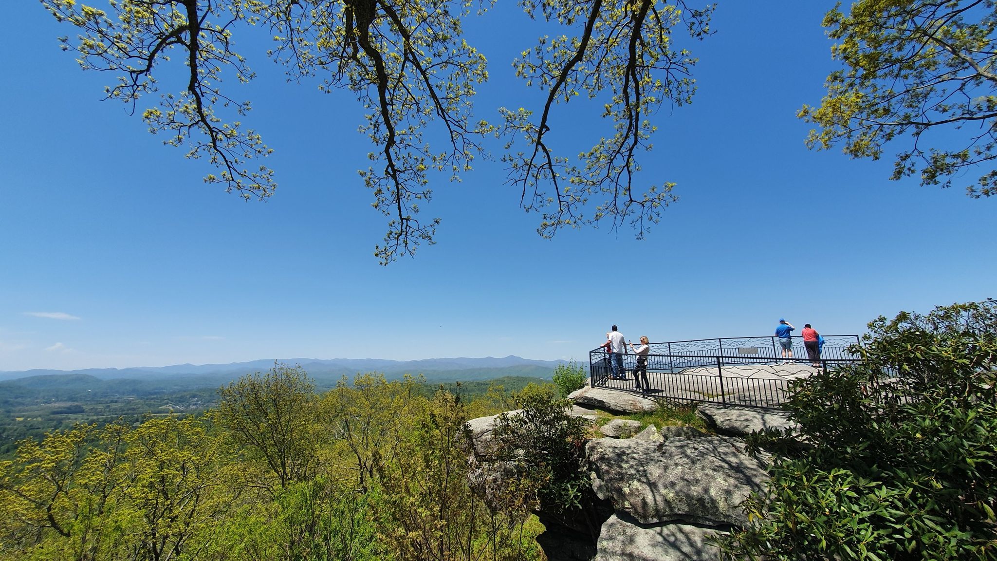 People on a sunny mountain overlook, enjoying the expansive view. - Jump Off Rock Blue Trail