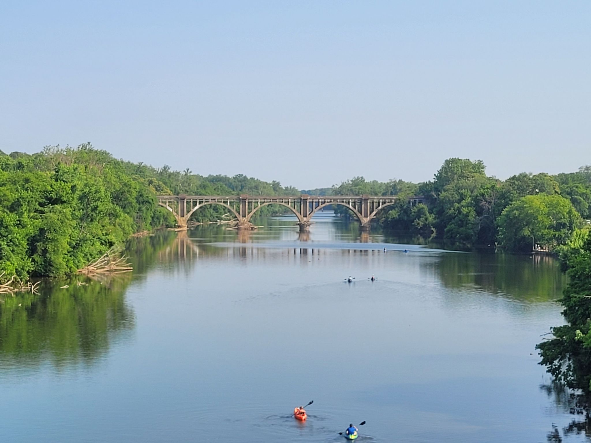Kayakers on a wide river under an arched bridge on a clear day. - Scotts Island loop from Fredericksburg