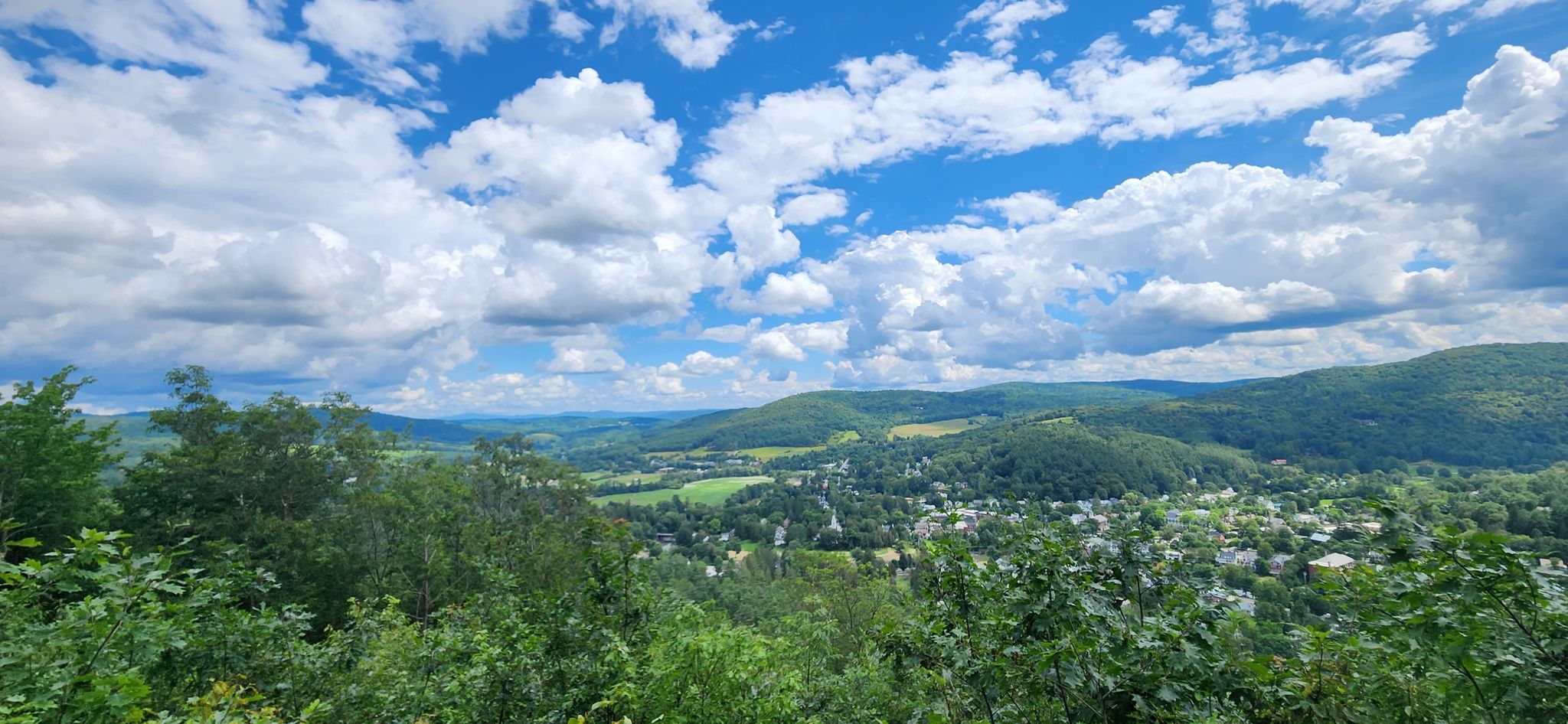 Expansive view of green rolling hills and a town under a cloudy sky. - Mount Tom loop via the Faulkner Trail