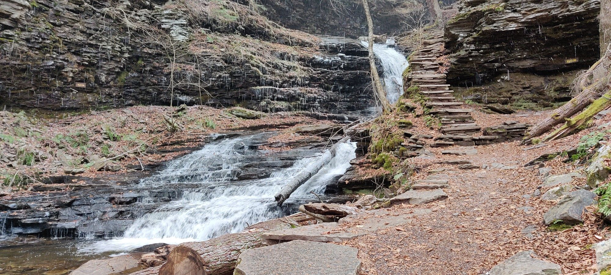 Waterfall cascading beside a stone staircase and rocky forest path. - B. Reynolds Falls – Beautiful break place loop from Ricketts Glen State Park