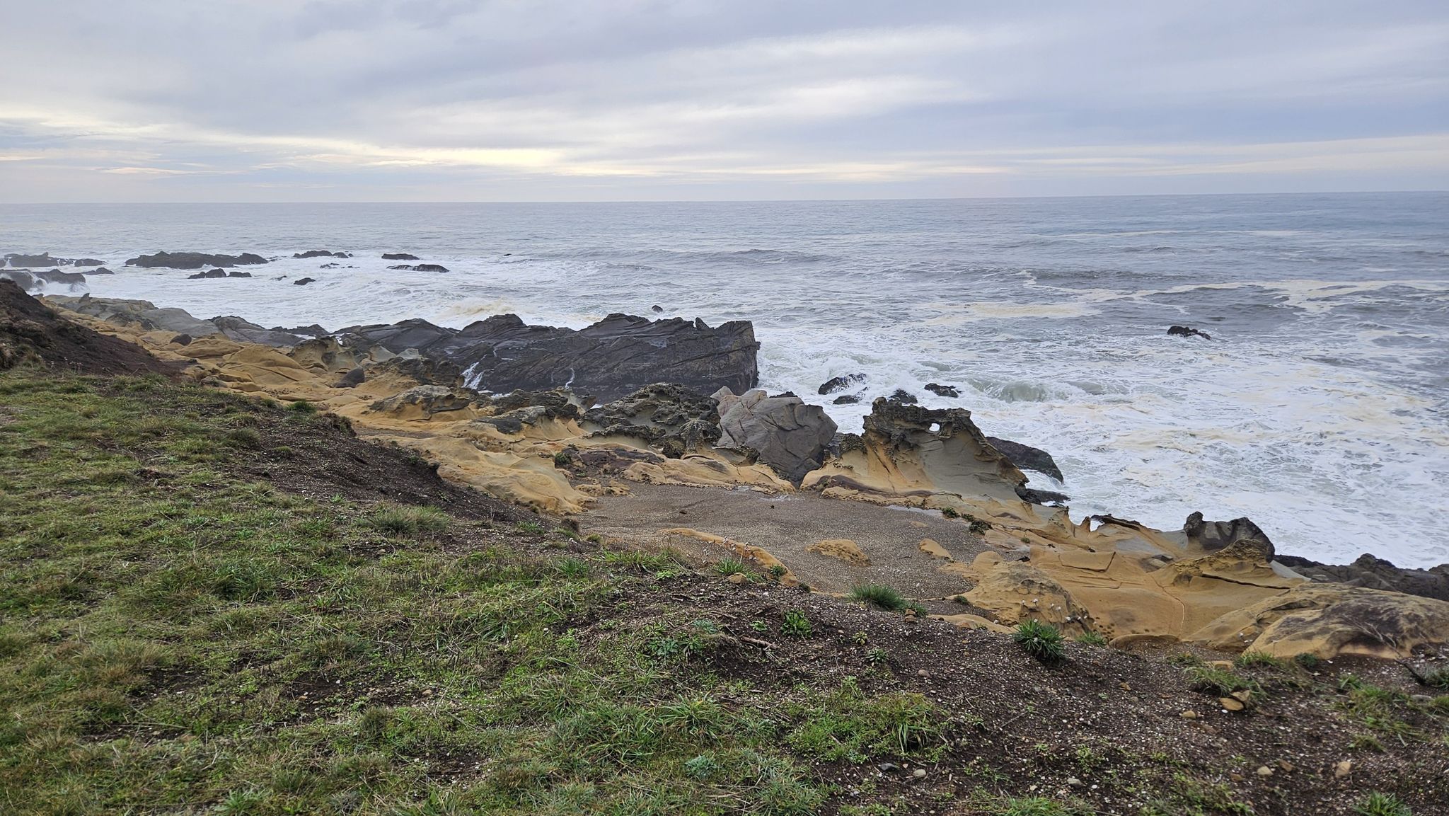Overcast view of a rugged, eroded rocky shore with turbulent ocean waves. - Salal Cove loop from Gualala