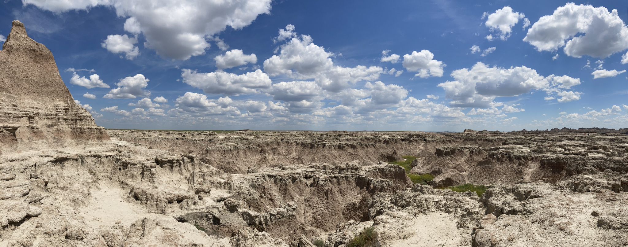 Panoramic view of a rugged, eroded landscape under a blue sky with clouds. - Door Trail