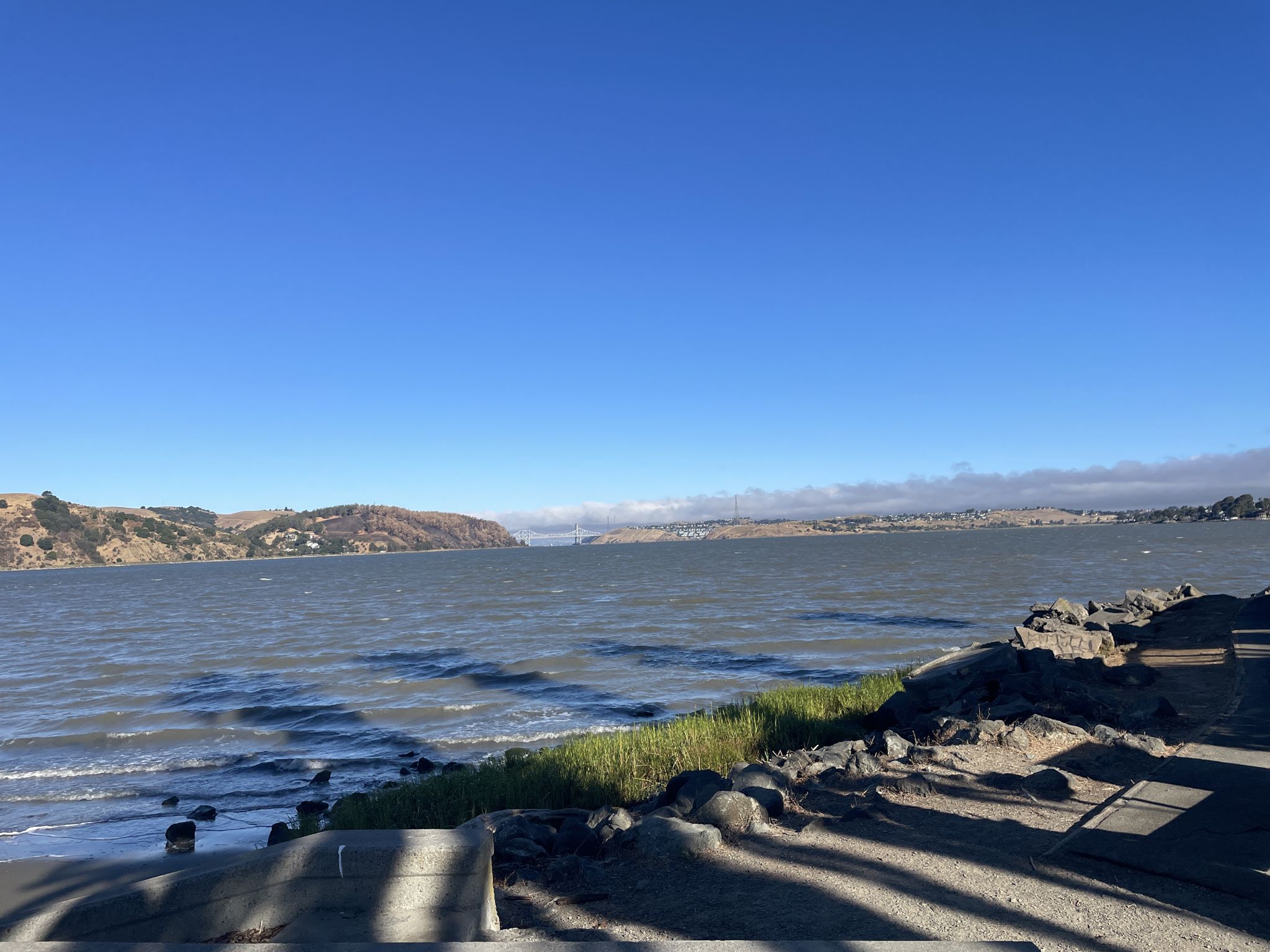 Wide shot of a large body of water, distant hills, and rocky shore. - San Francisco Bay Trail: Benicia Waterfront