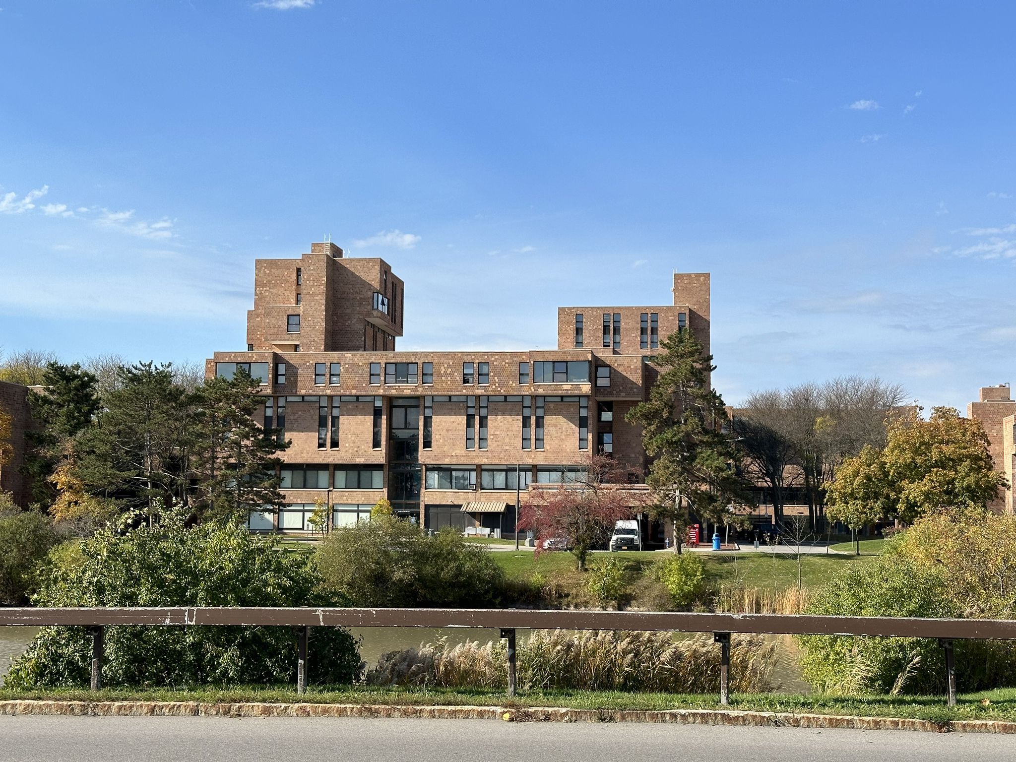 A large, multi-story brick building surrounded by trees on a sunny day. - Clarence Akron Peanut Line Bike Pathways and Tonawanda Rails-to-Trails loop