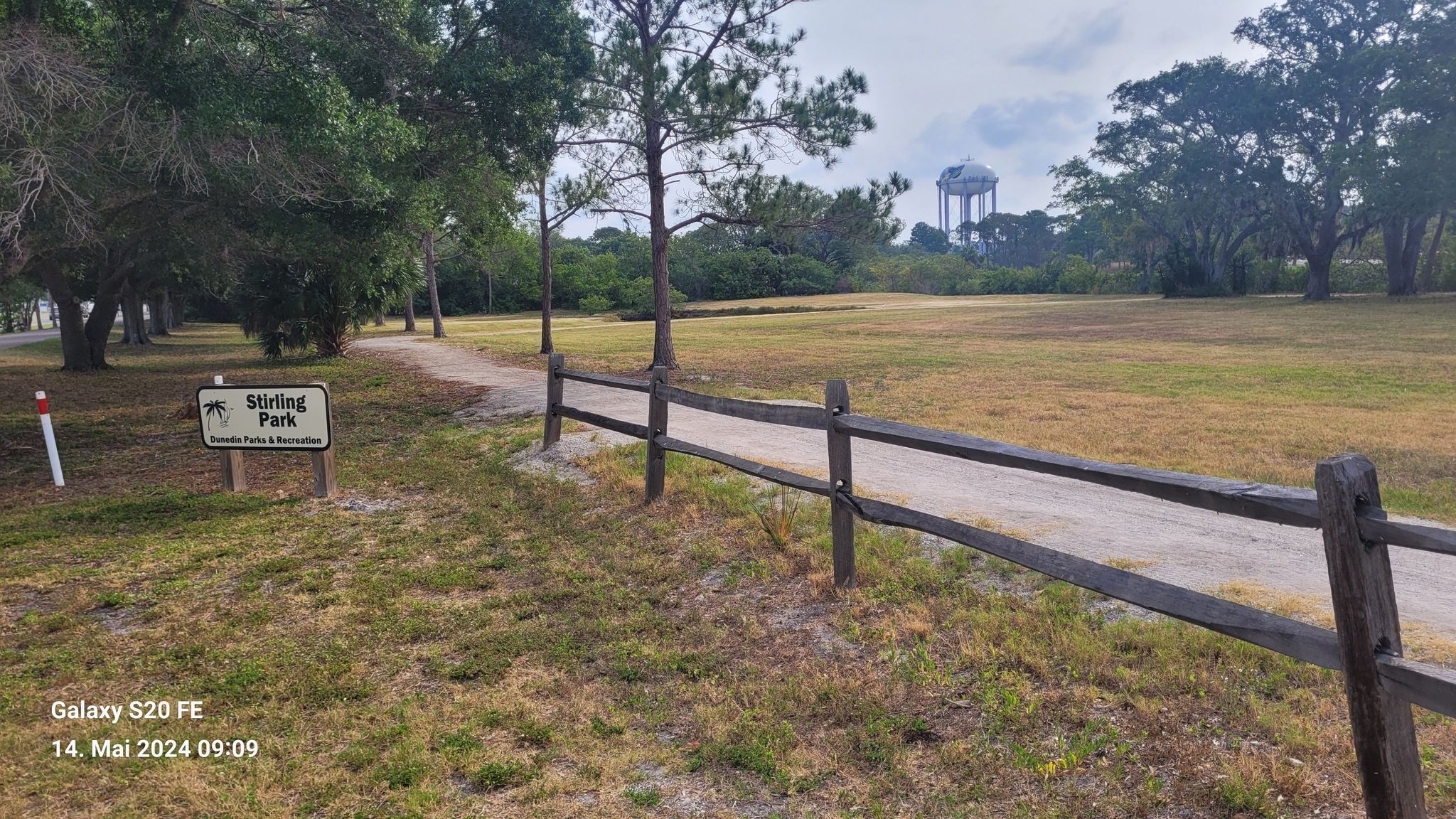 A dirt path next to a wooden fence, leading through a grassy field. - Dunedin – Pinellas Trail loop from Clearwater Executive Airport