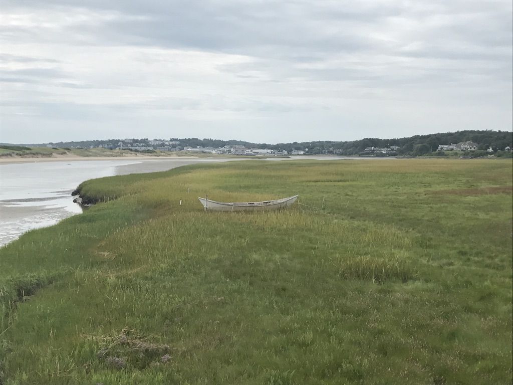 An old boat rests in a green marsh beside a calm waterway under cloudy skies. - Webhannet Drive to Post Road loop