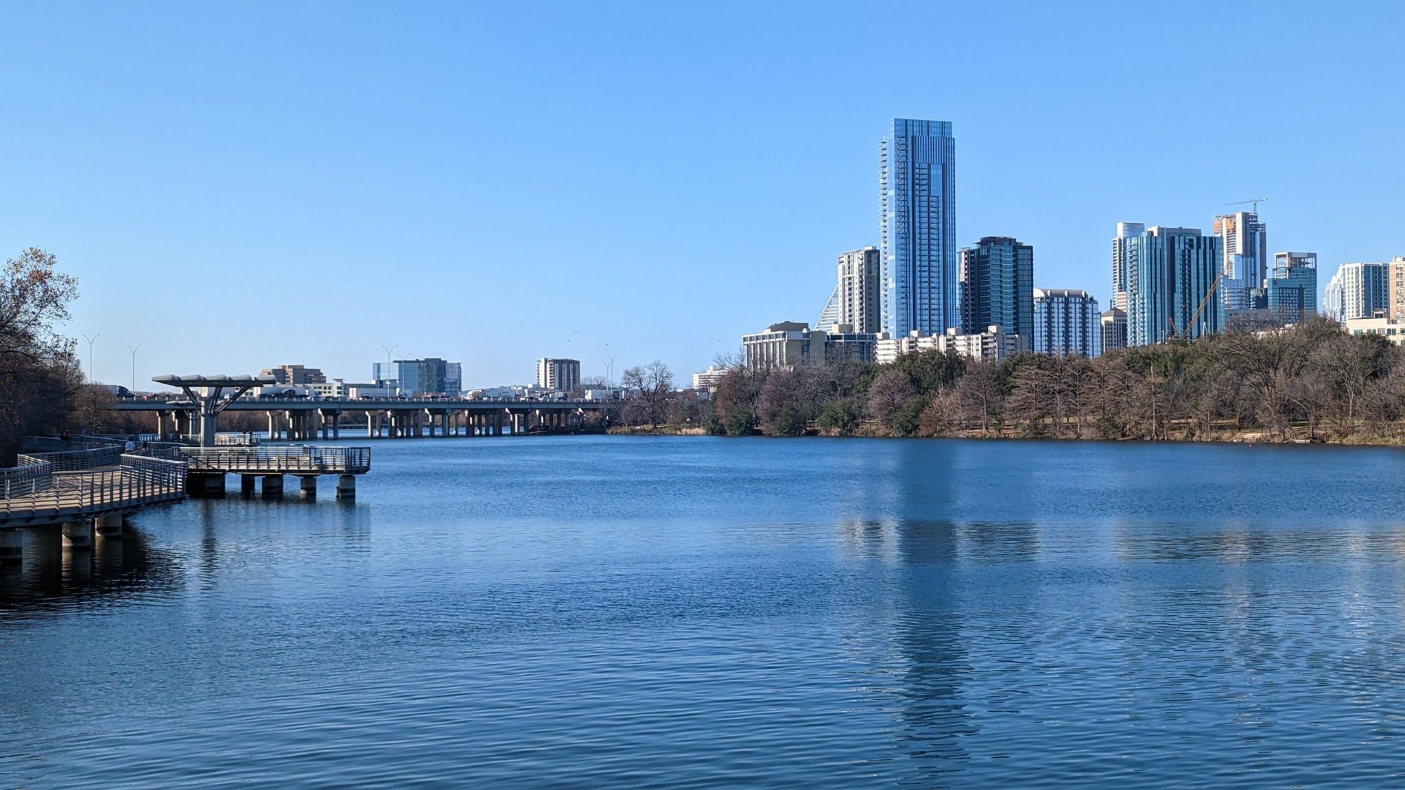 City skyline across a wide river with a boardwalk on a clear day. - Boardwalk – Longhorn Point loop from Huston-Tillotson University