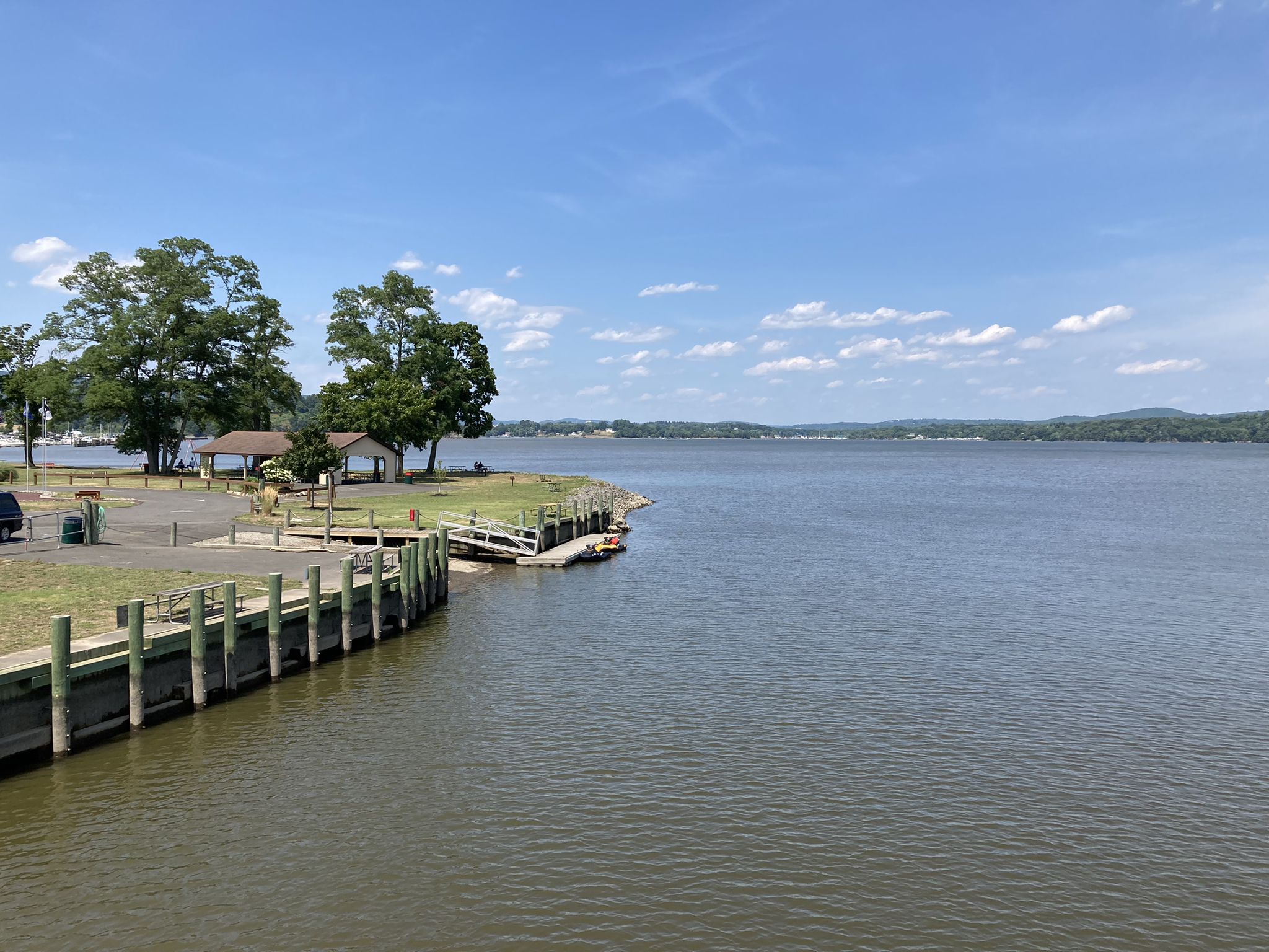 Sunny view of a wide waterway with docks and forested hills in the distance. - South Mountain Road Loop