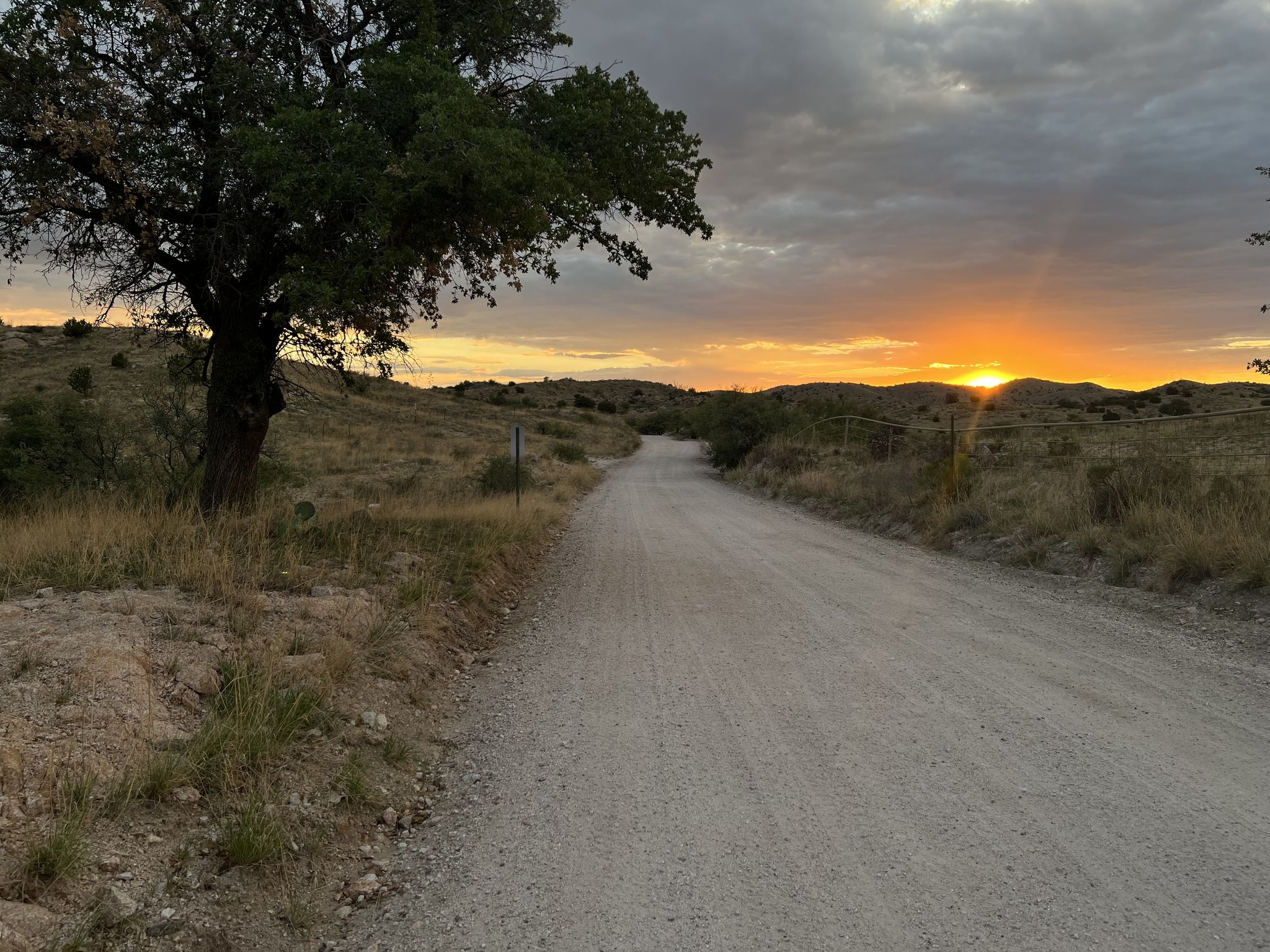 Dirt road at sunset with golden light and cloudy sky over hills. - Chiva Falls Loop via Arizona Trail