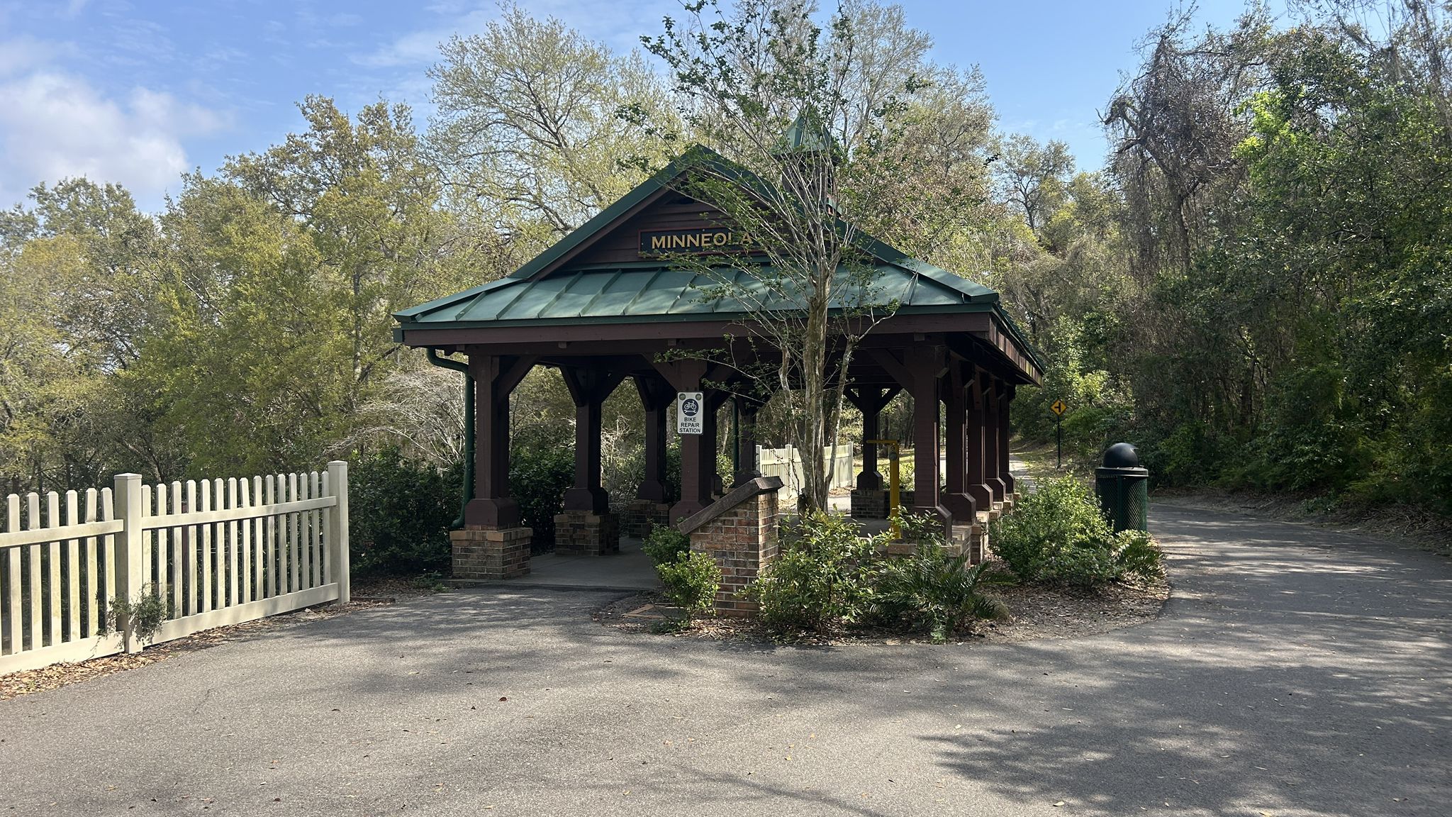 Sunny day with a wooden gazebo surrounded by trees and a white fence. - Roadbike loop from Minneola