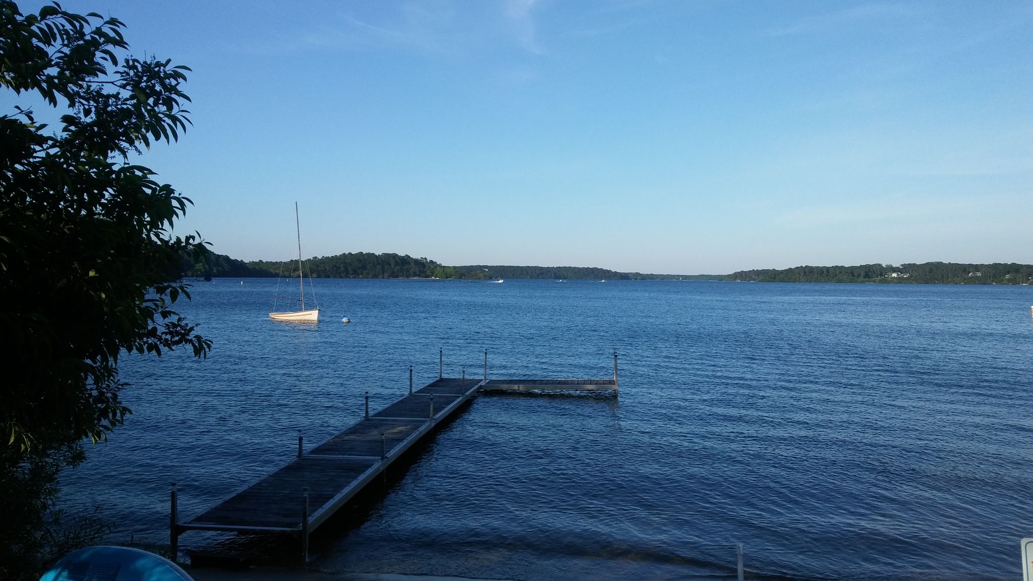 Long wooden dock in a calm blue lake with a distant sailboat. Sunny. - Pleasant Lake (Hinckleys Pond) – Seymour Pond loop from Flax Pond