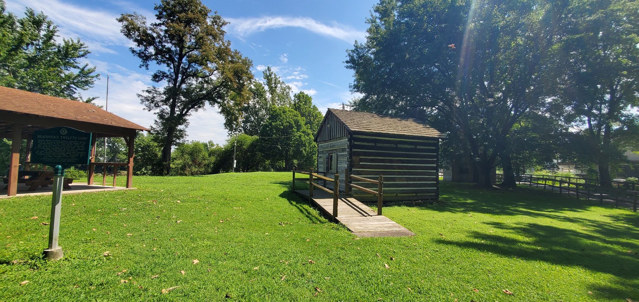 A small wooden cabin with a ramp on green grass under a sunny sky. - Connellsville loop