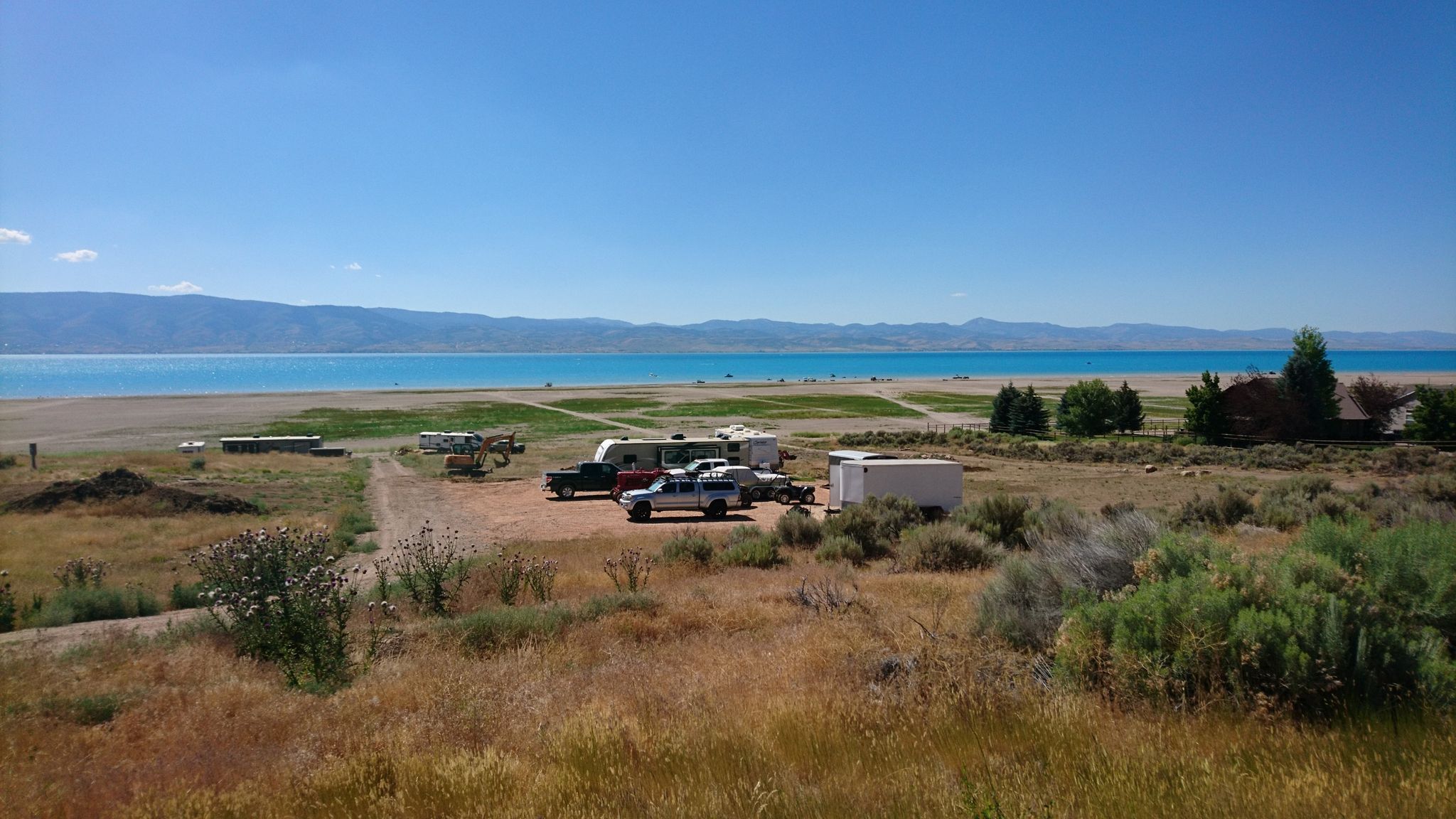 RVs and trucks parked on a dry, grassy shore next to turquoise water. - North Beach – North Cisco Road loop from Logan Canyon Scenic Bypass