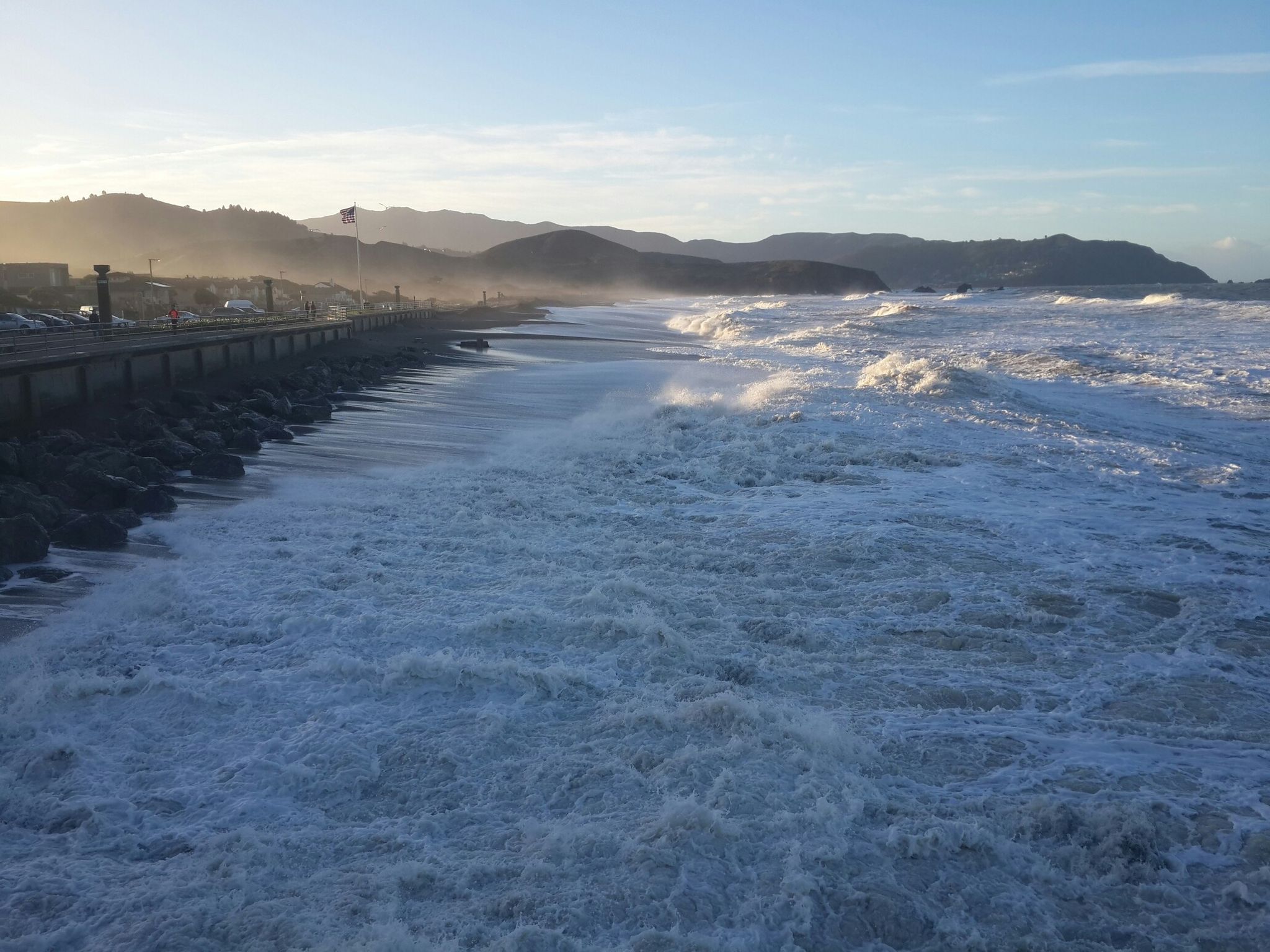 Powerful ocean waves crash against a rocky coastline with distant hazy mountains. - Pacifica Beach Boulevard North – Pacifica Pier loop from Milagra Ridge