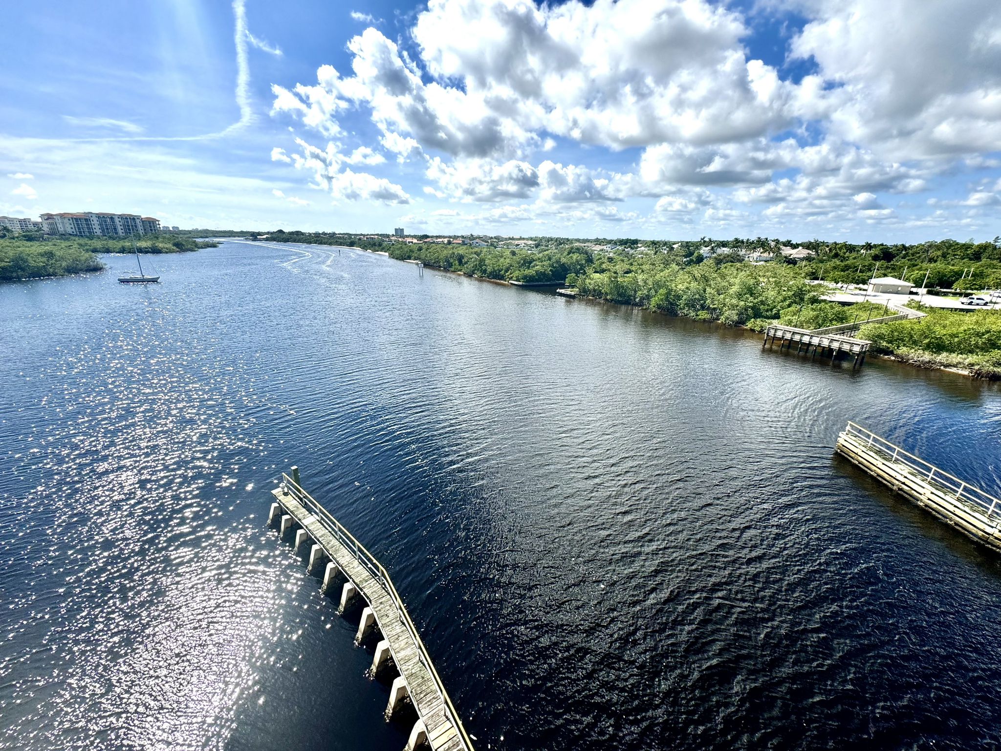 A wide river with docks and distant buildings under a bright, cloudy sky. - Jupiter Beach Park to Hobe Sound Beach & Johnatahan Dickson State Park loop