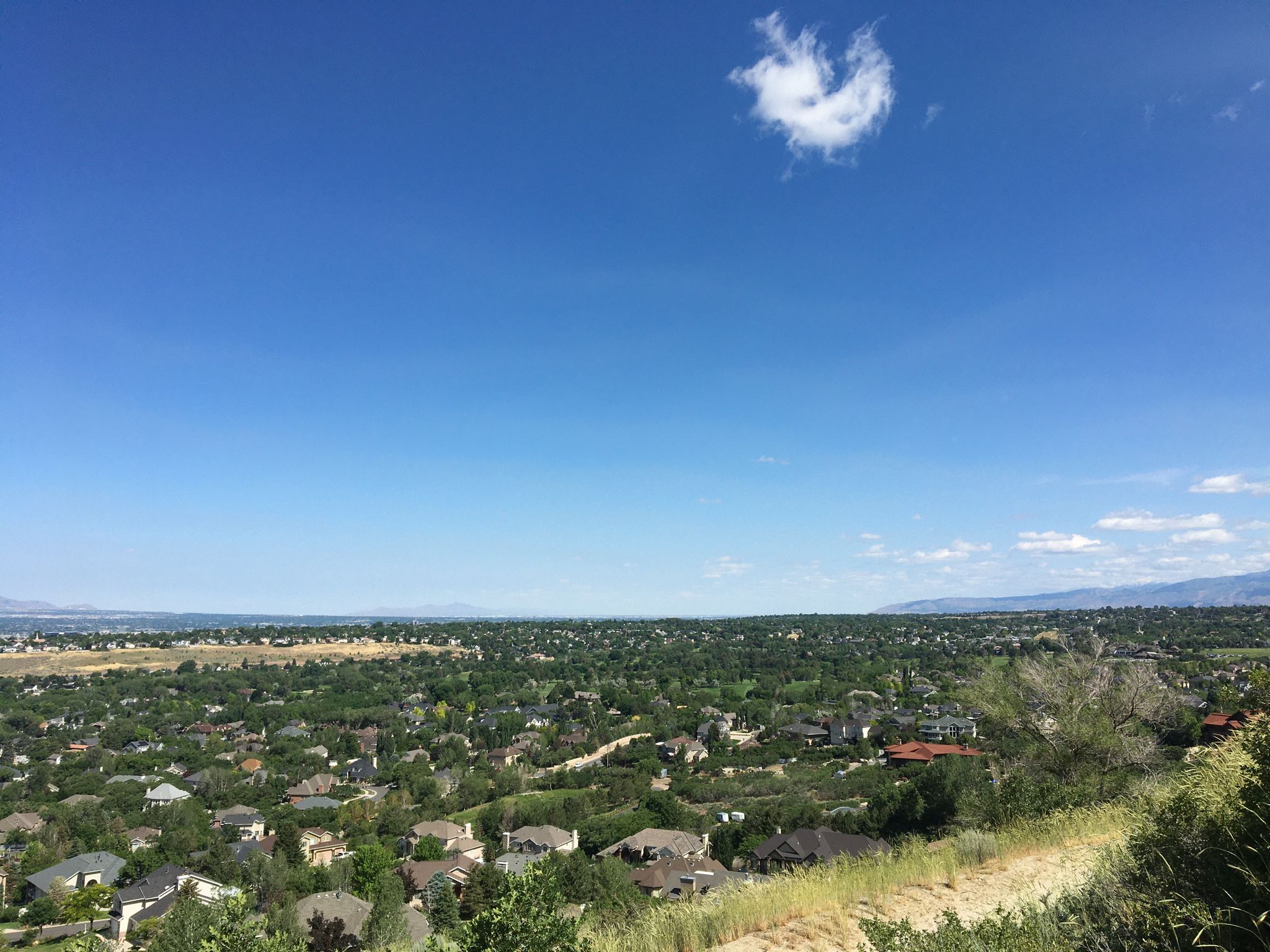 Panoramic view of a valley with houses and green trees under a clear blue sky. - Enniss Peak Loop