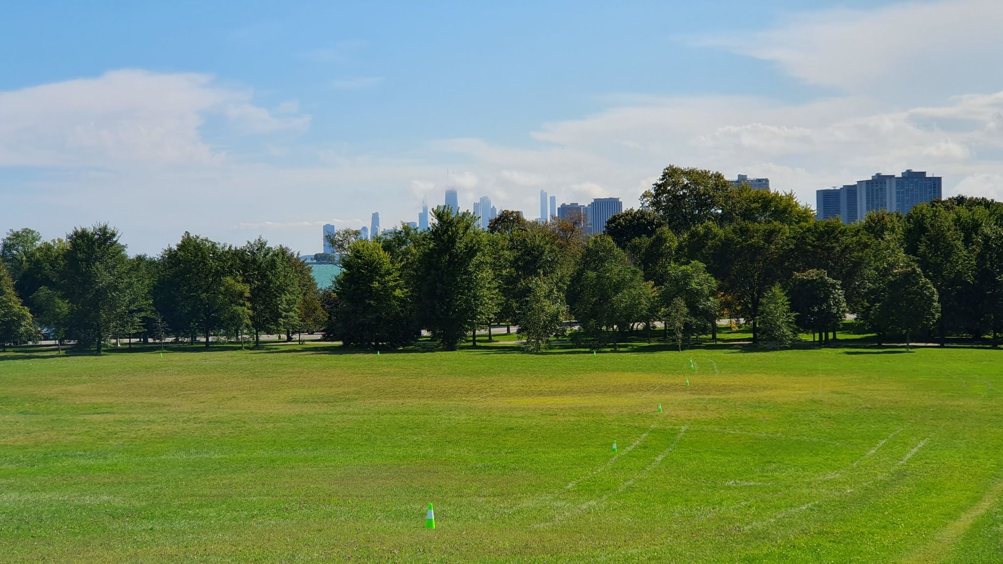 Expansive green field with distant trees and city skyline under a blue sky. - North Shore Channel and Lakefront Trail Loop