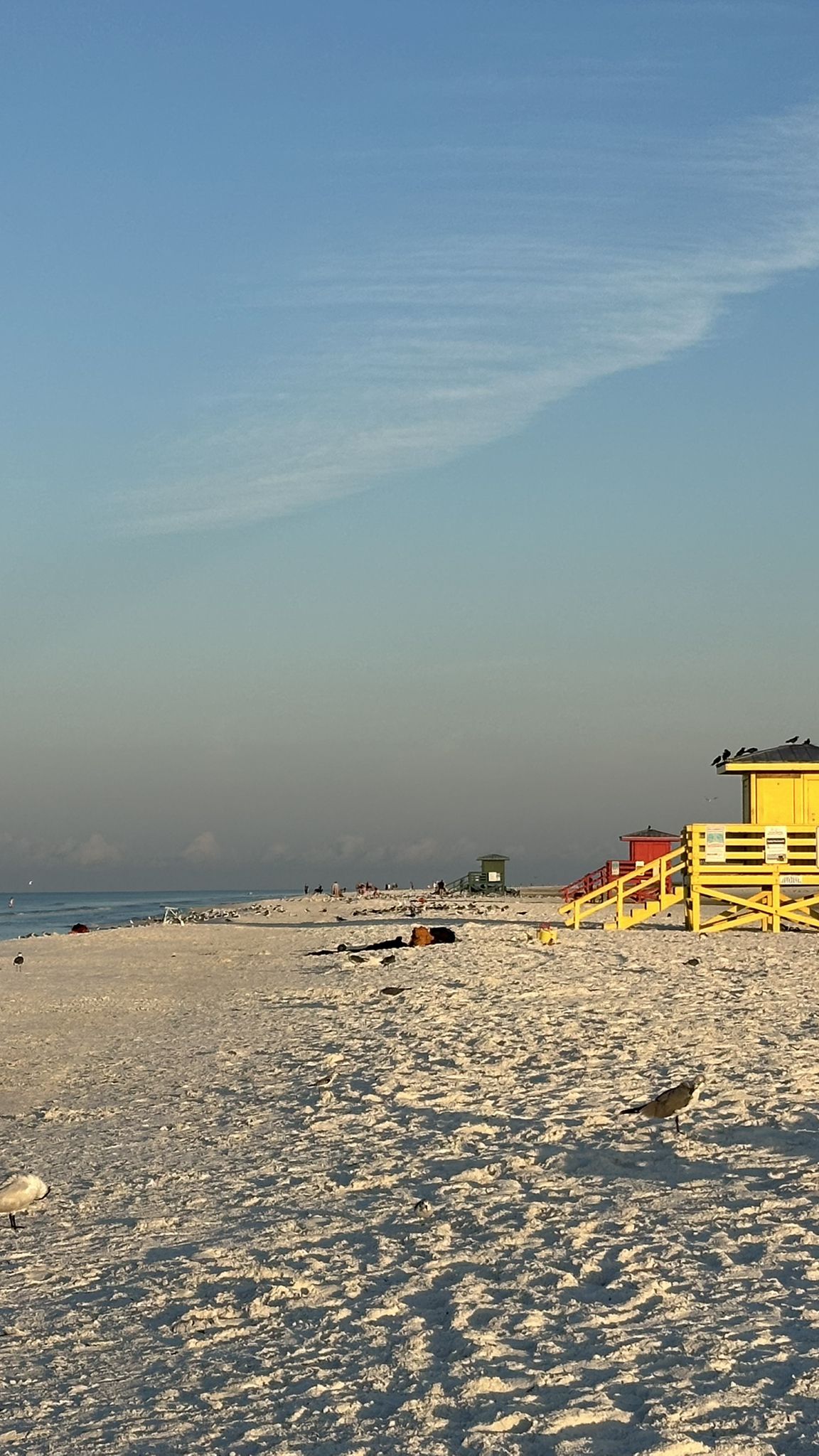 Sandy beach with yellow and red lifeguard stands under a soft, clear sky. - Crescent Beach – Siesta Key Beach loop from Siesta Key