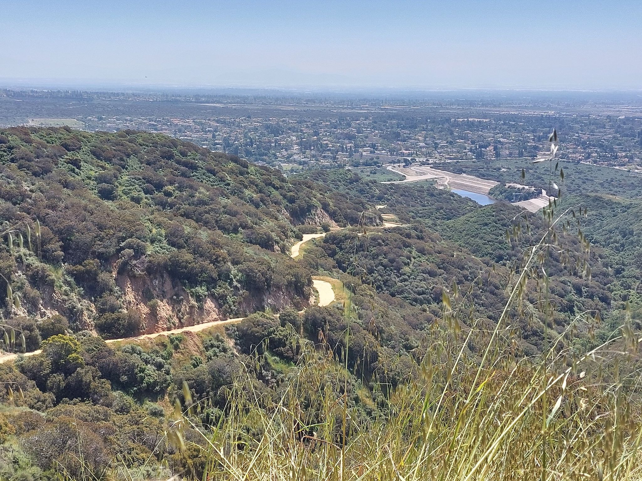 Winding dirt road on a hillside overlooking a city and distant water. - Burbank Trail – Marshall Canyon Trail loop from Valero