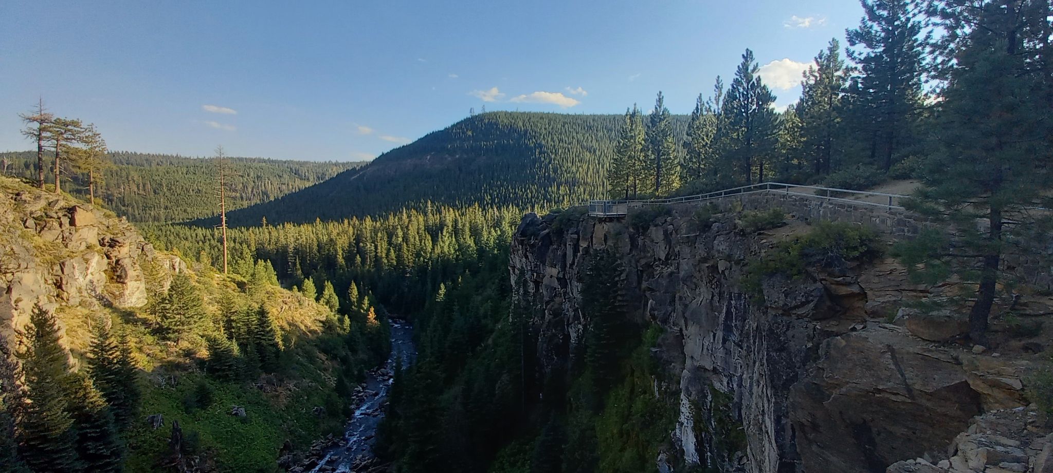 Panoramic view of a wide, forested canyon with a river below. - Tumalo Falls – Tumalo Falls (Lower Viewpoint) loop from Bend