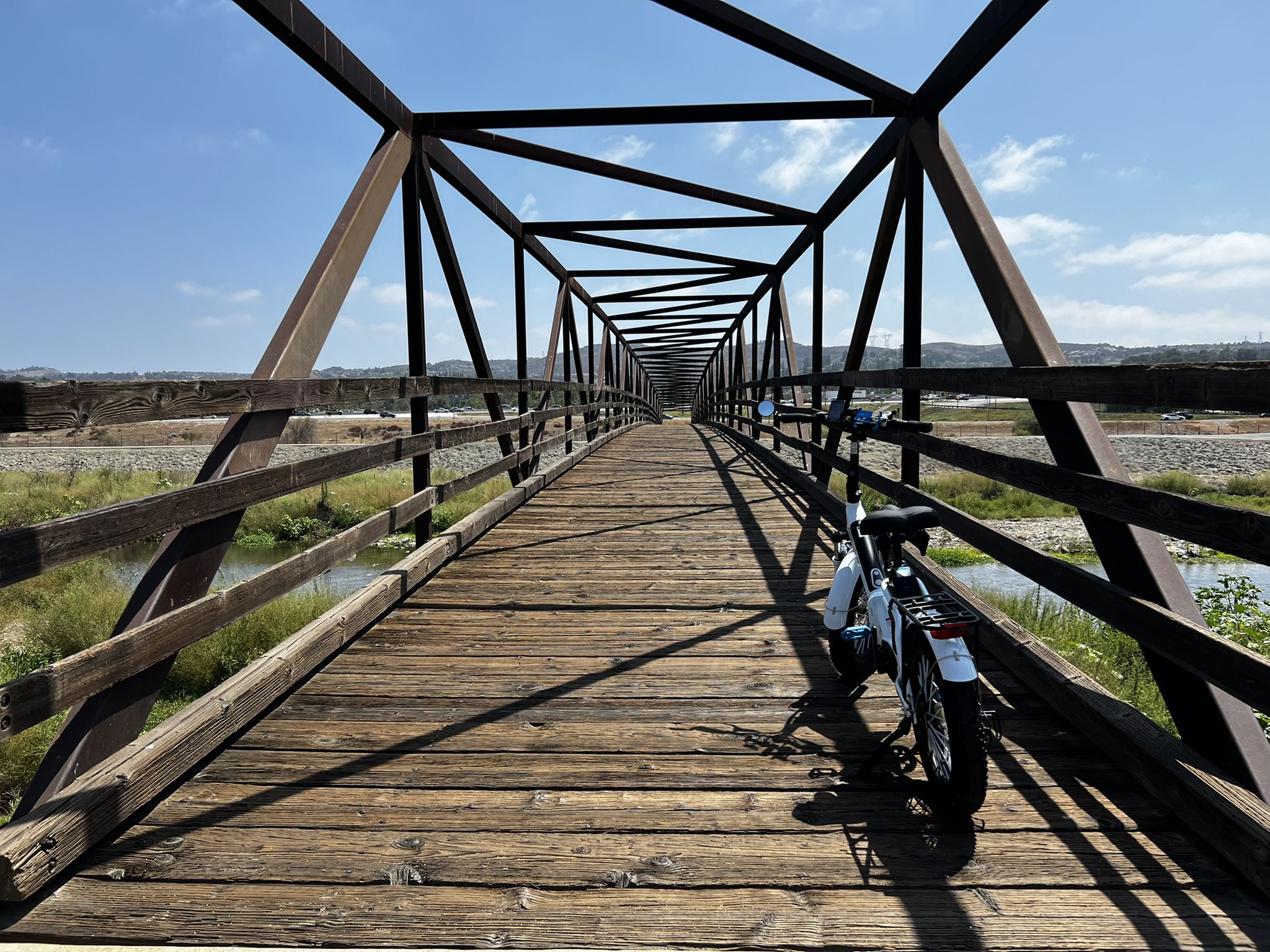 Bicycle parked on a long wooden and metal truss bridge on a sunny day. - Santa Ana River – Santa Ana River Trail Bridge loop from Arroyo Park