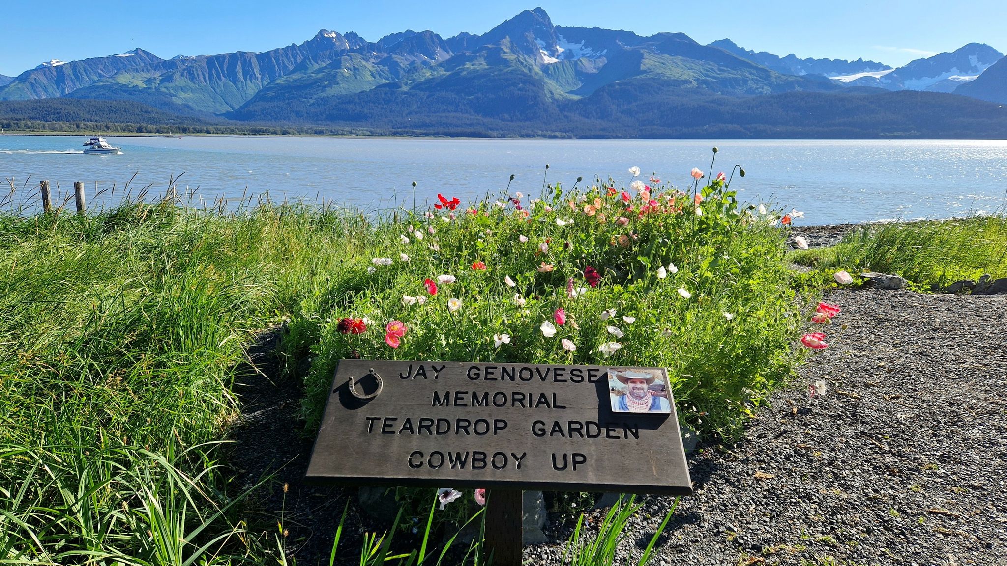 Memorial sign in a flower garden overlooking water and sunny forested mountains. - Seward Waterfront Shore Path