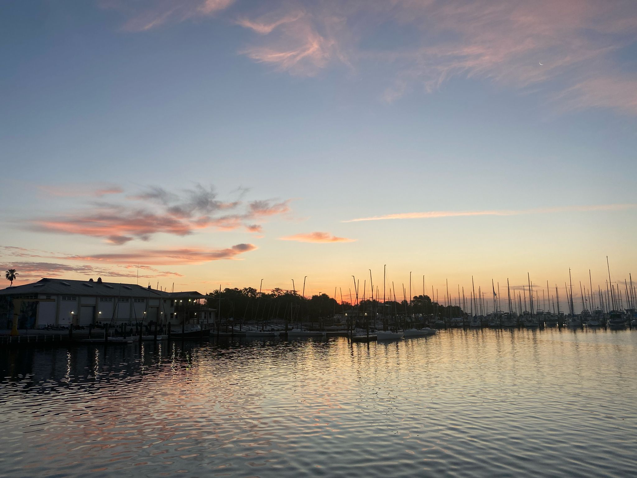 Marina with many sailboats at sunset, reflecting colorful sky on calm water. - Pinellas Trail – Demens Landing Park loop from Gulfport