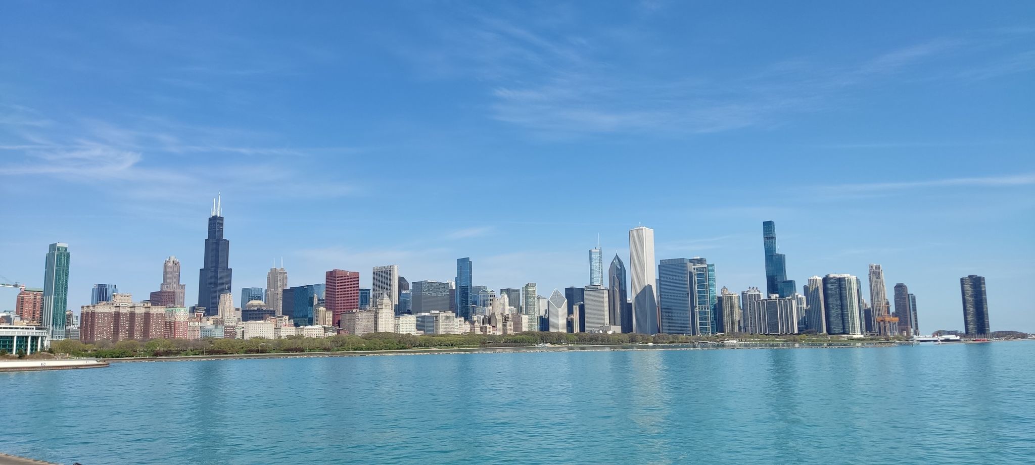 Distant city skyline across a wide body of water under a clear blue sky. - Lakefront Trail
