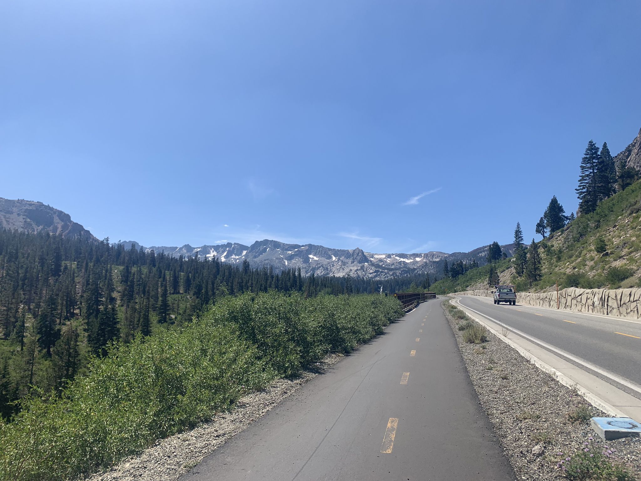 Paved path and road alongside a forested valley with snowy mountains. - Mountain View & Mammoth Rock Trail loop — Inyo National Forest